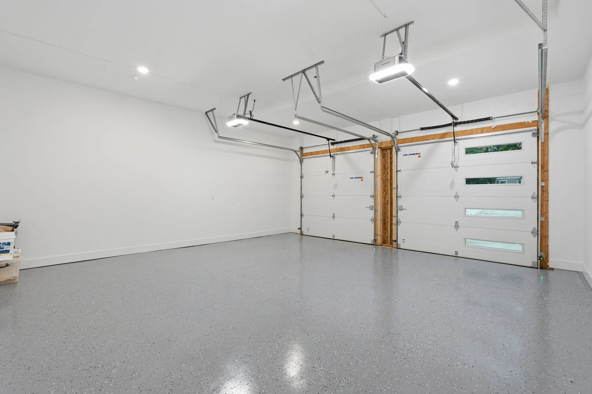 Two-car garage with white doors and gray epoxy flooring