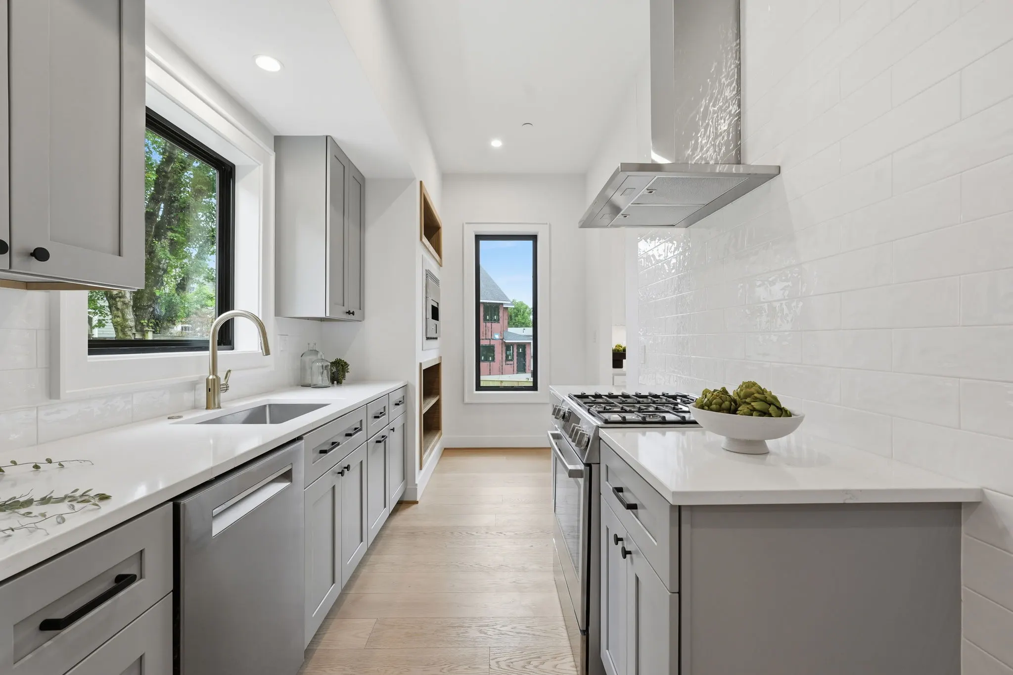 Galley kitchen with gray cabinets, white subway tile, and gas range