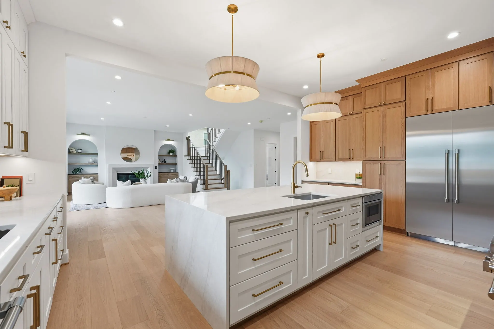 Kitchen with white island, wood and white cabinetry, stainless appliances