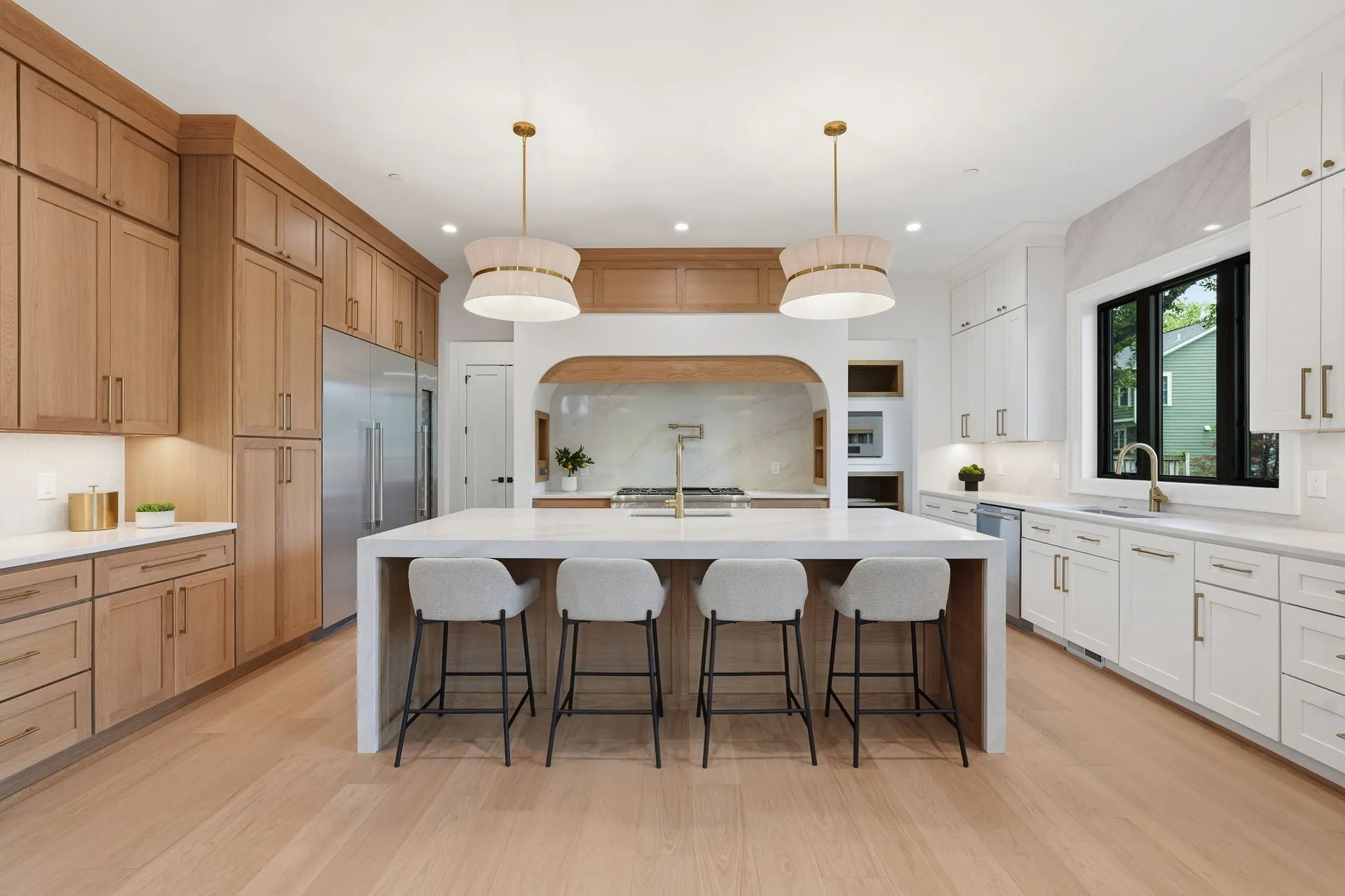 Kitchen with white island, wood and white cabinetry, multiple pendant lights
