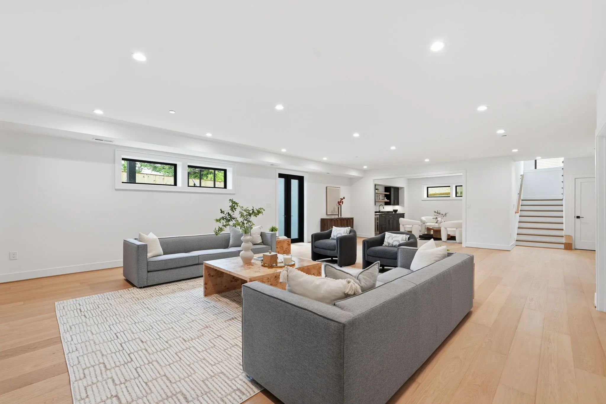 Basement recreation room with gray seating and wood table