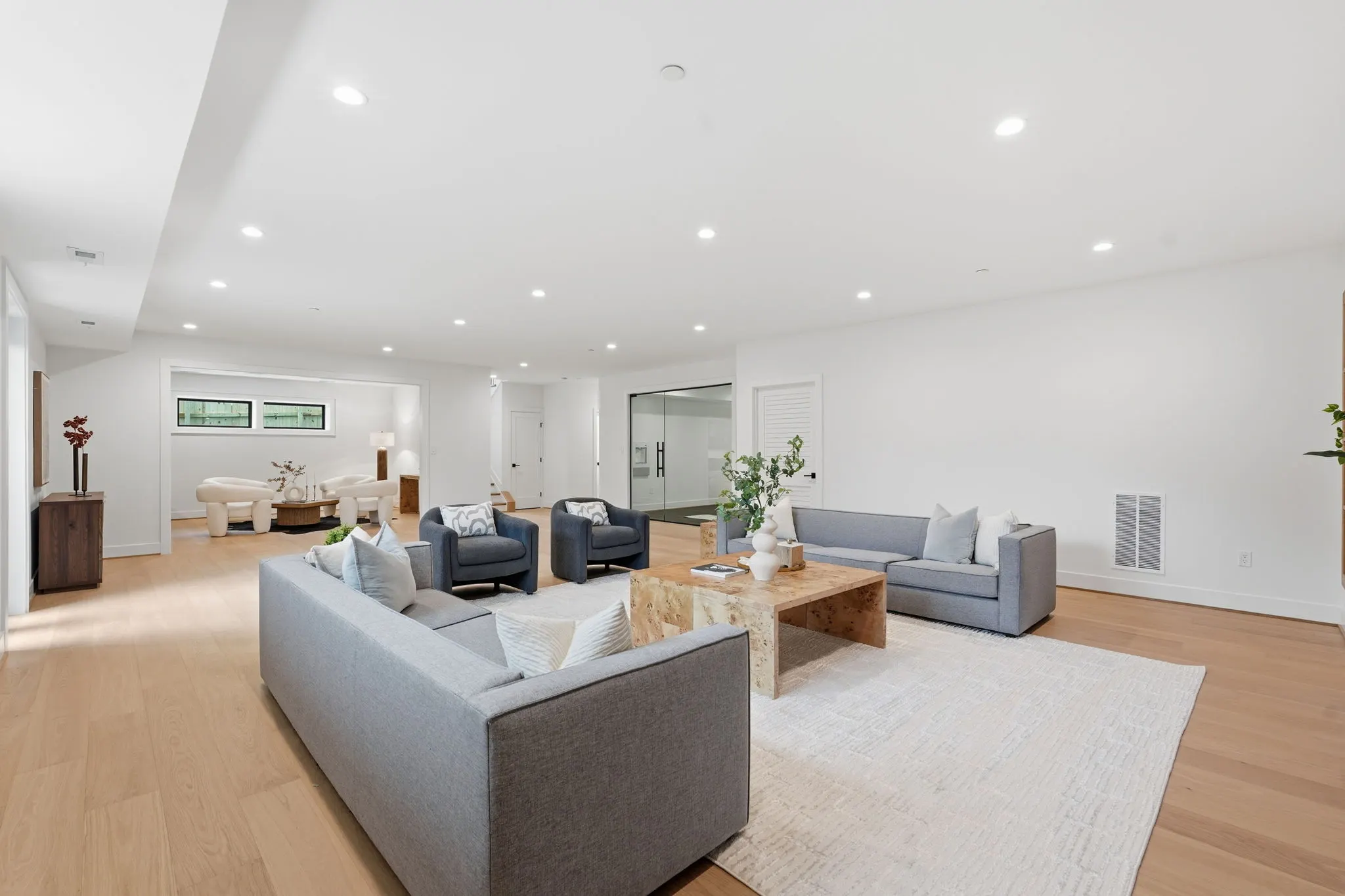 Open living space with gray sectional sofa and recessed ceiling lights