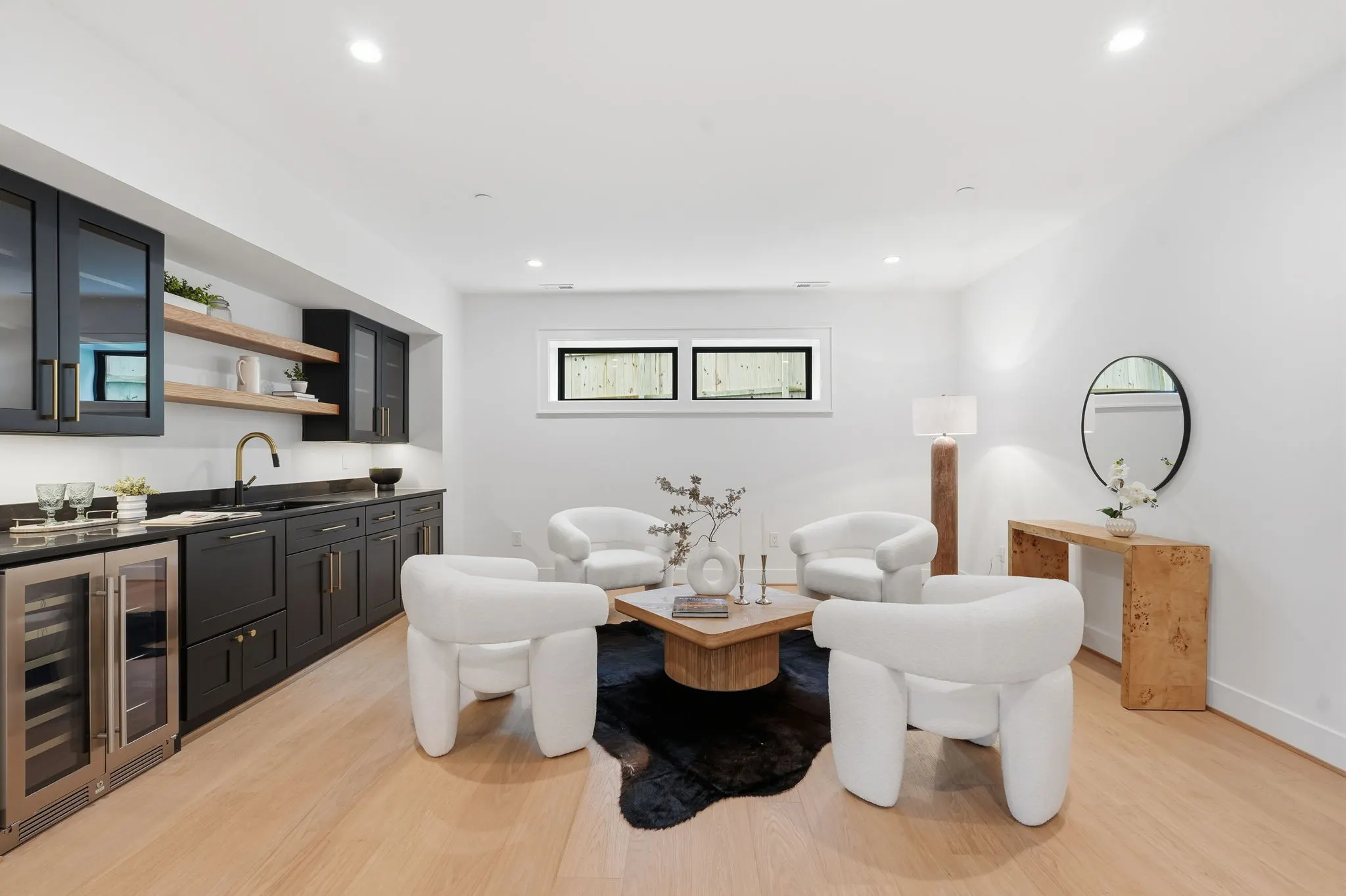 Wet bar with black cabinetry and white armchairs around wood table