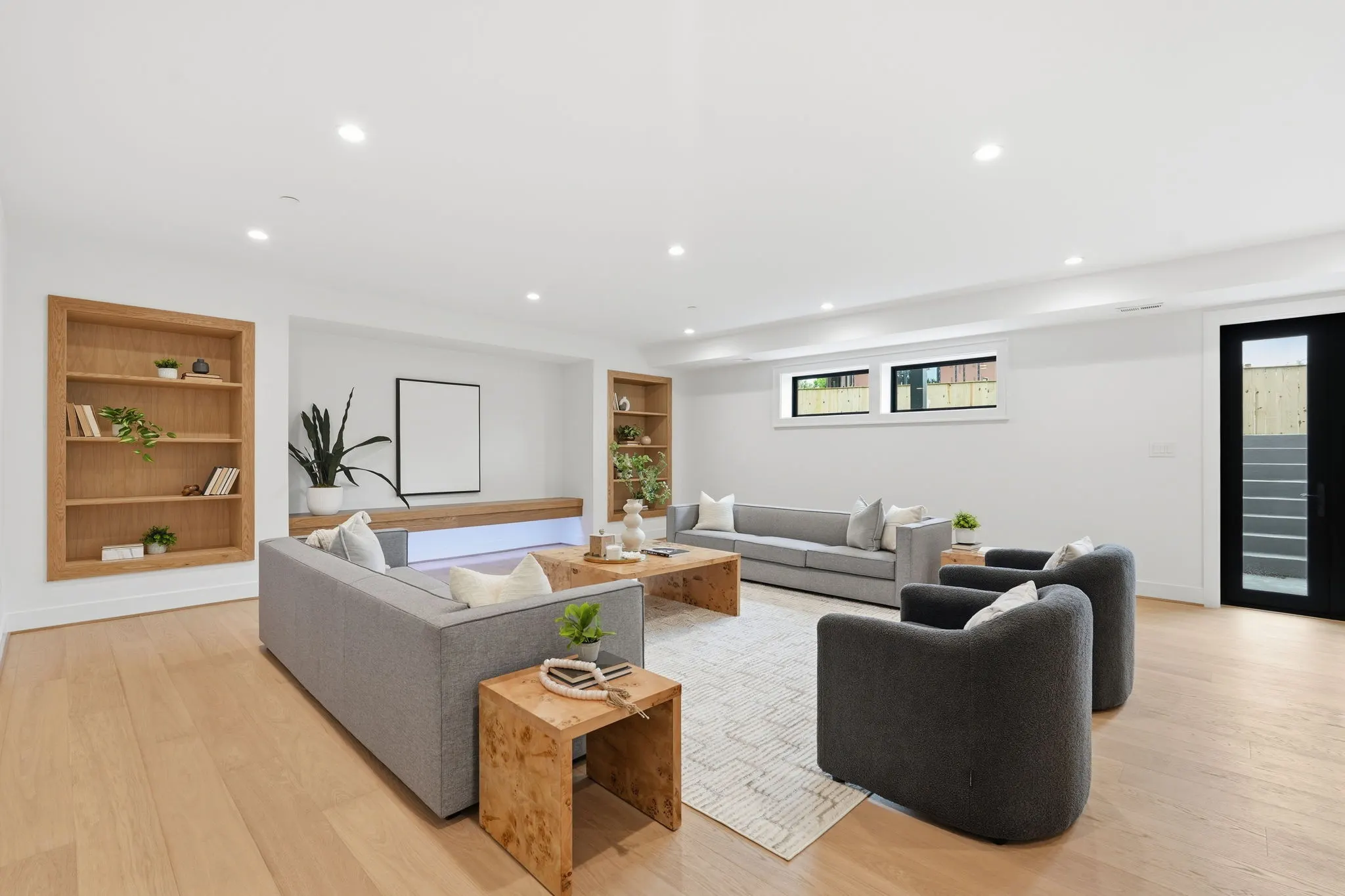 Open living room with gray sofas and wooden built-in shelving