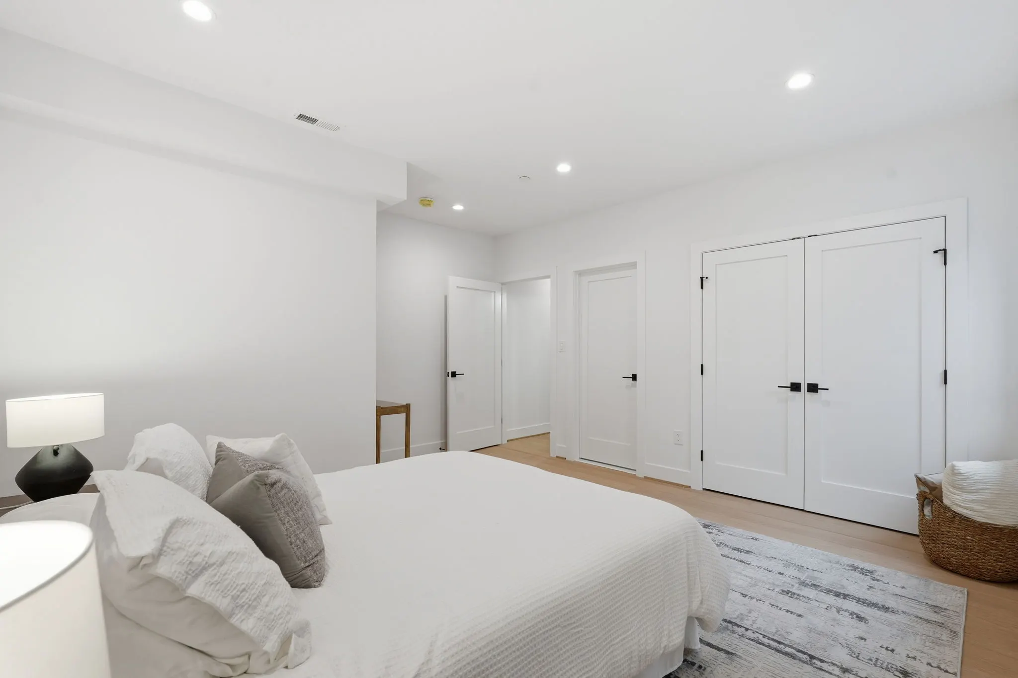 Primary bedroom with white bedding and multiple white closet doors