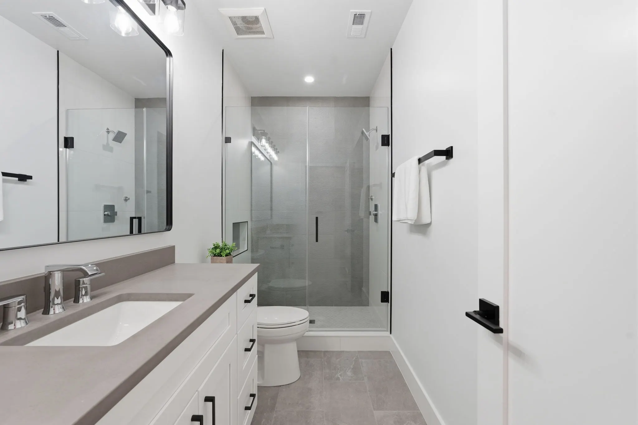 Bathroom with gray vanity, large mirror, and glass shower enclosure