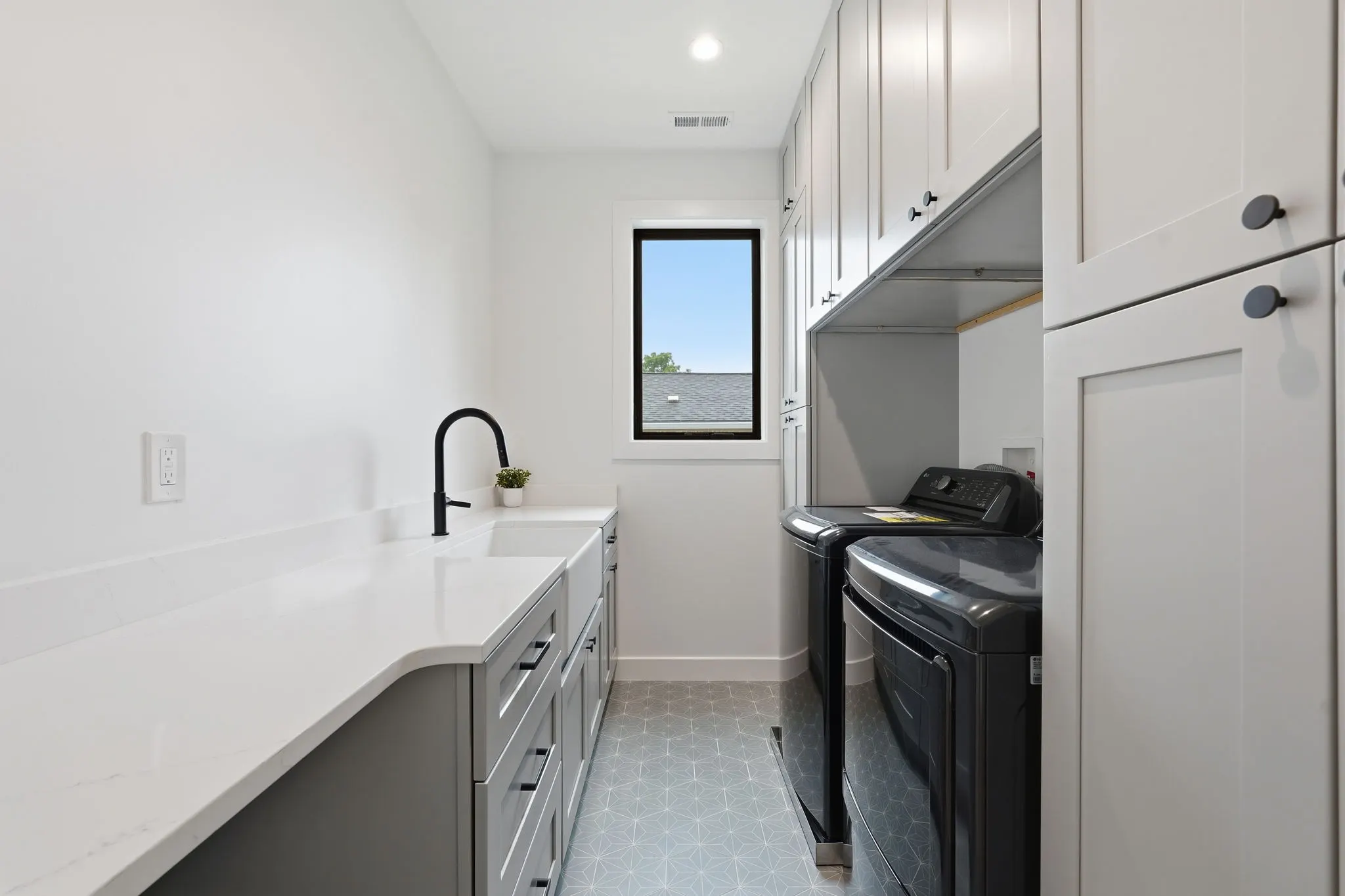 Laundry room with white cabinets and black washer and dryer