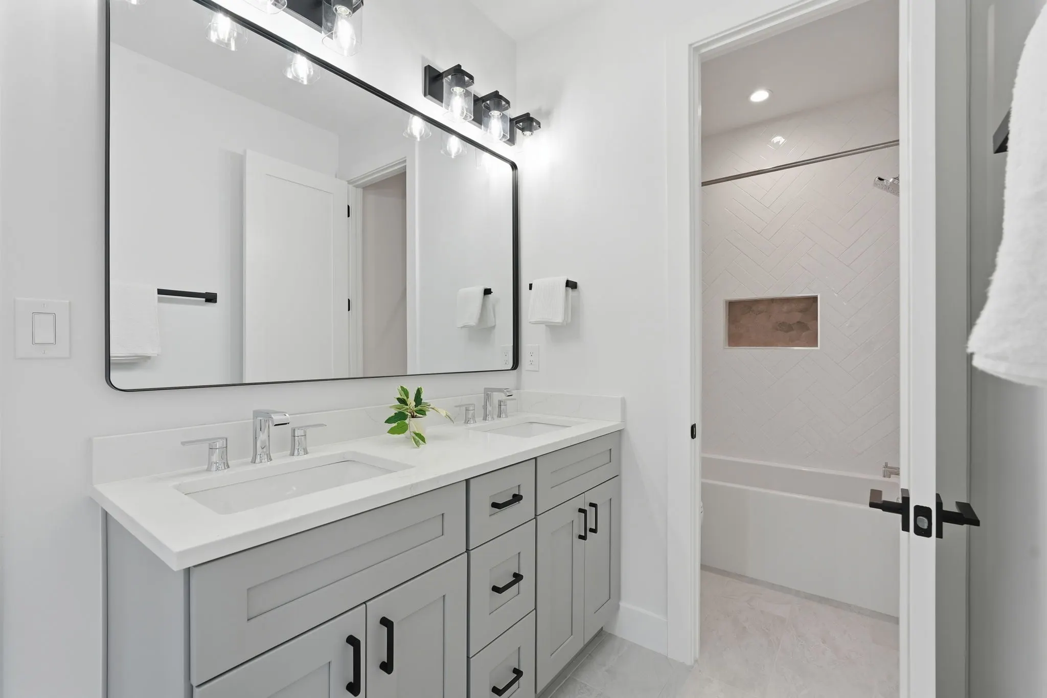 Bathroom with gray vanity, black-framed mirror, and ensuite shower area
