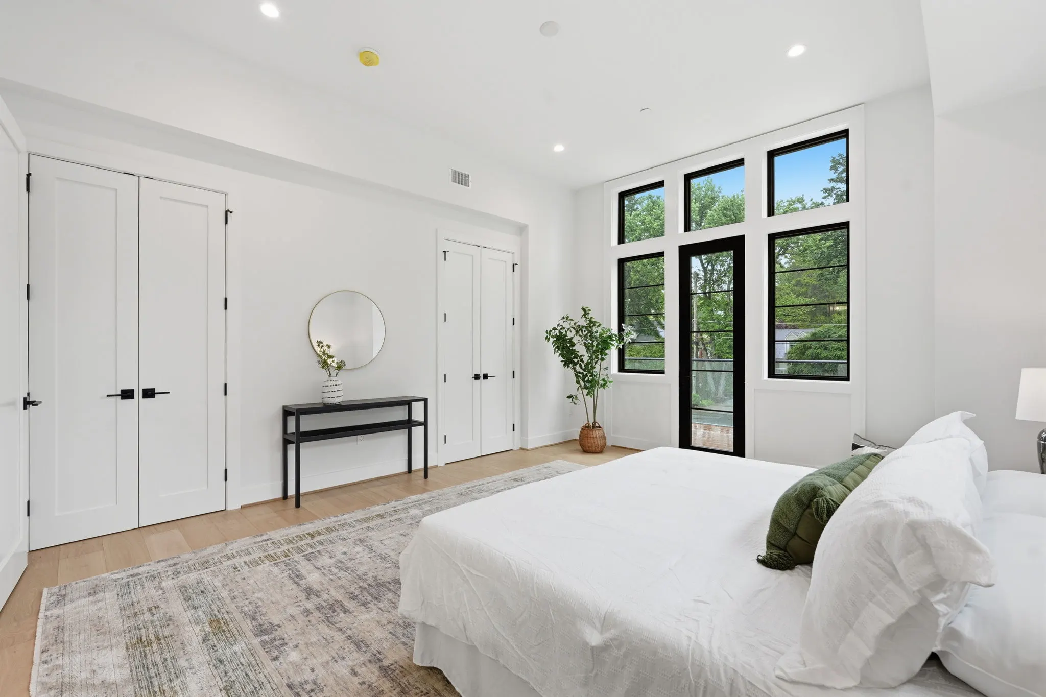 Primary bedroom with white closets and black-framed glass doors
