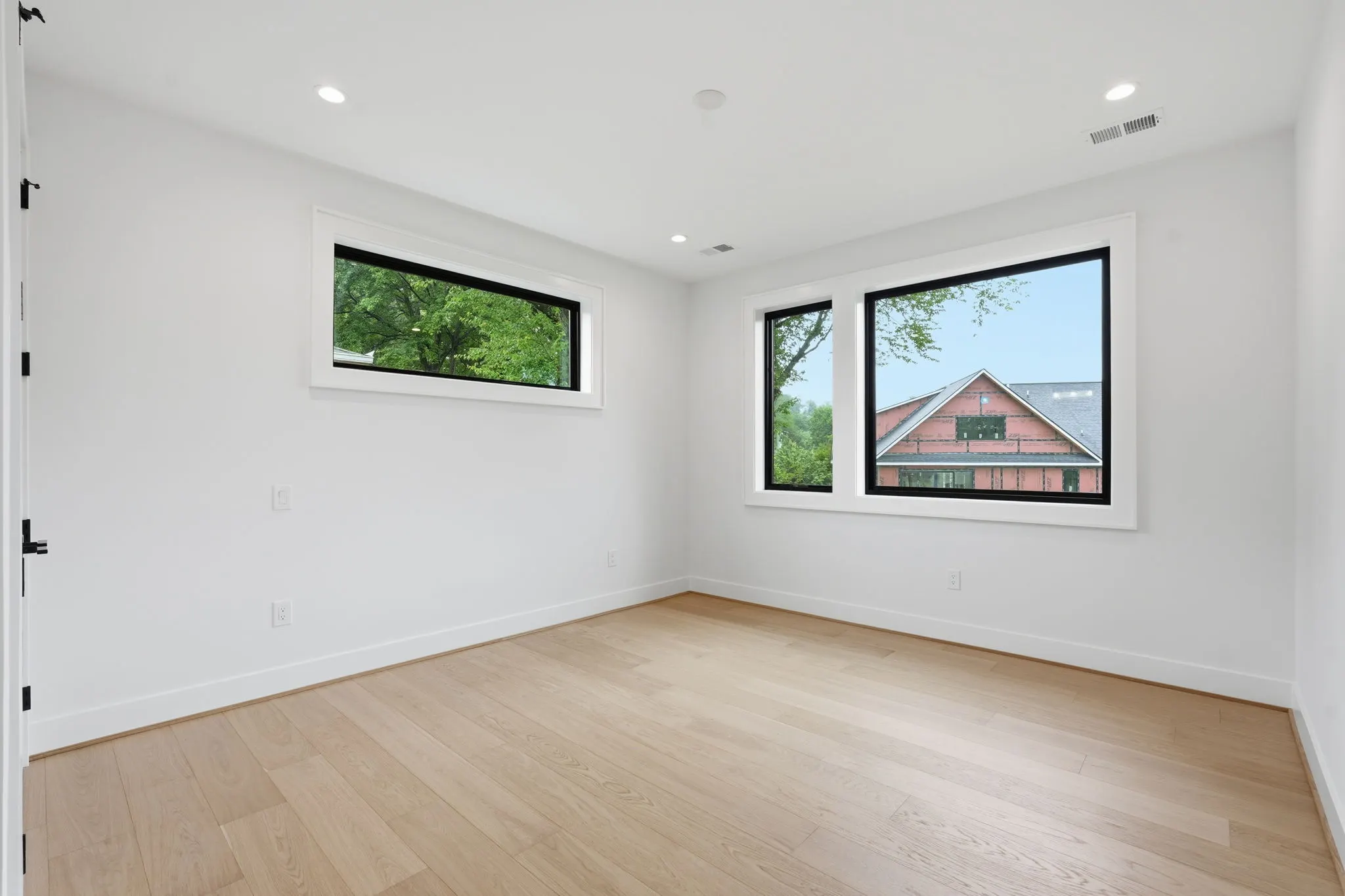 Empty bedroom with wood flooring and large windows