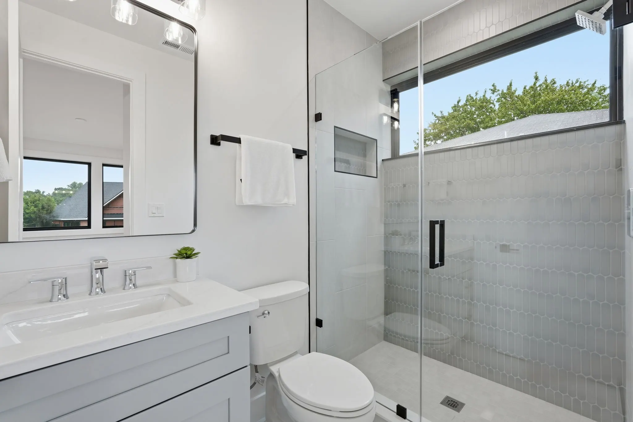Bathroom with gray tile shower and white dual vanity