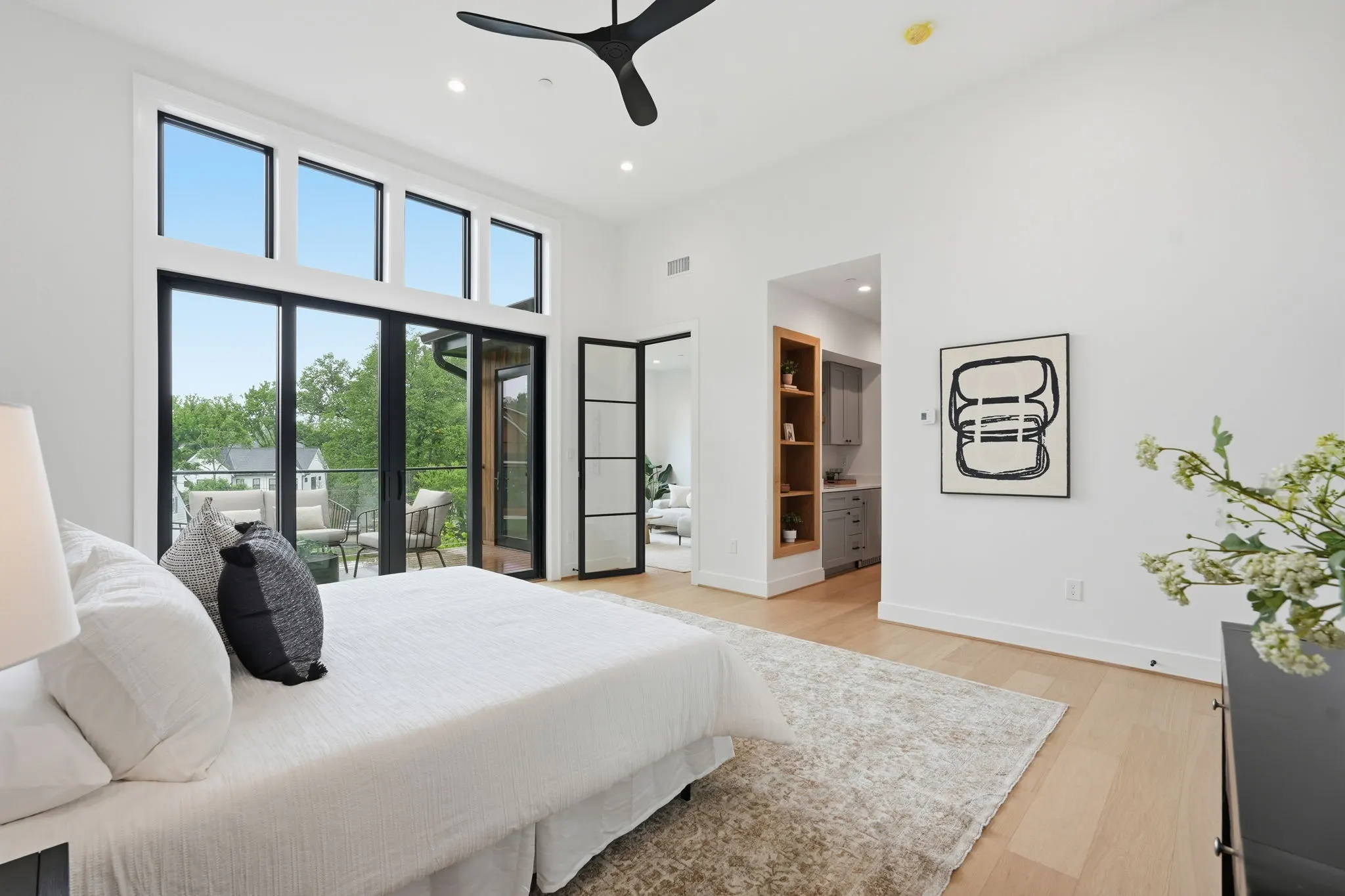 Primary bedroom with black framed glass doors opening to balcony