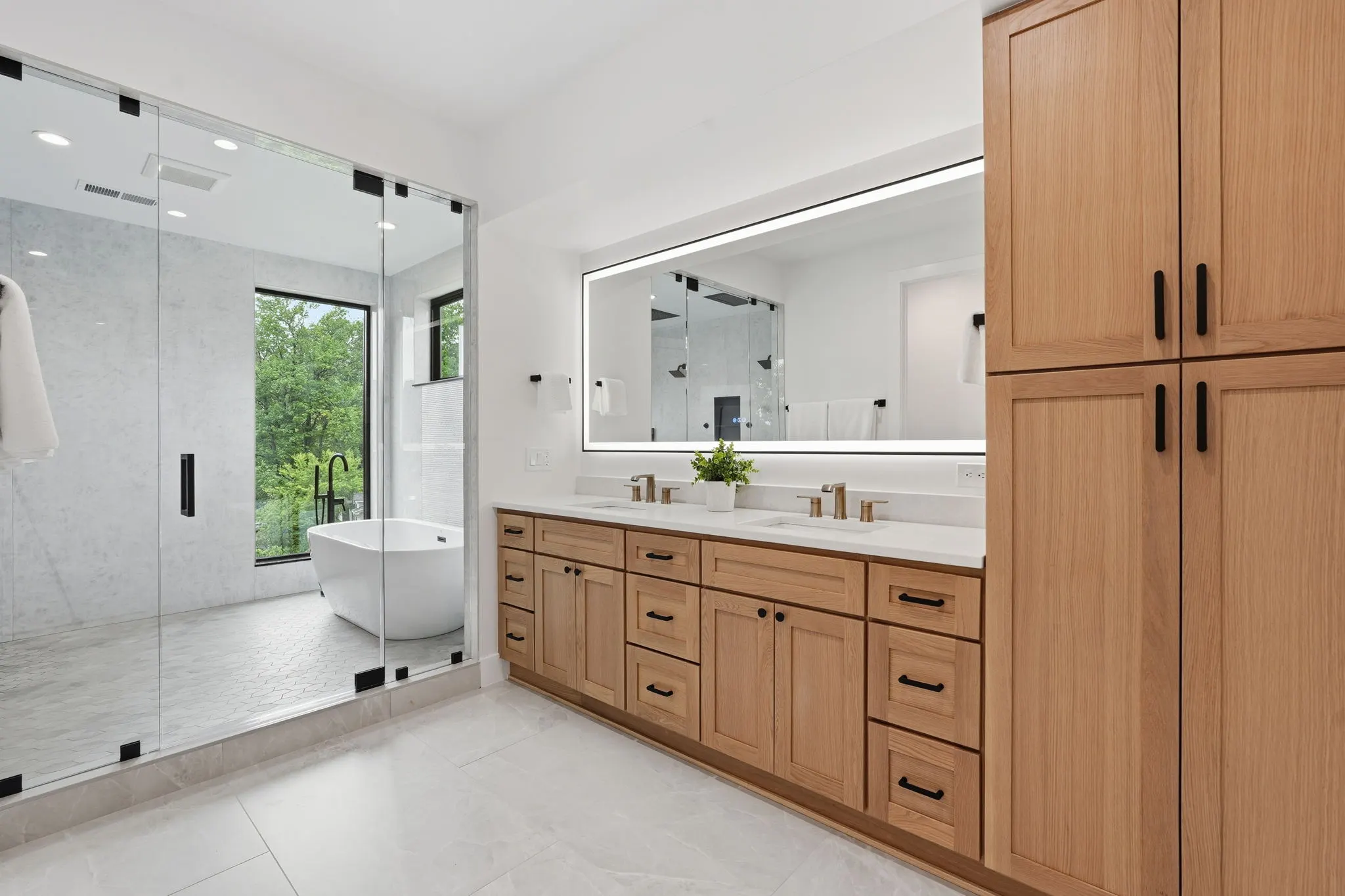 Primary bathroom with glass shower, freestanding tub, and double oak vanity