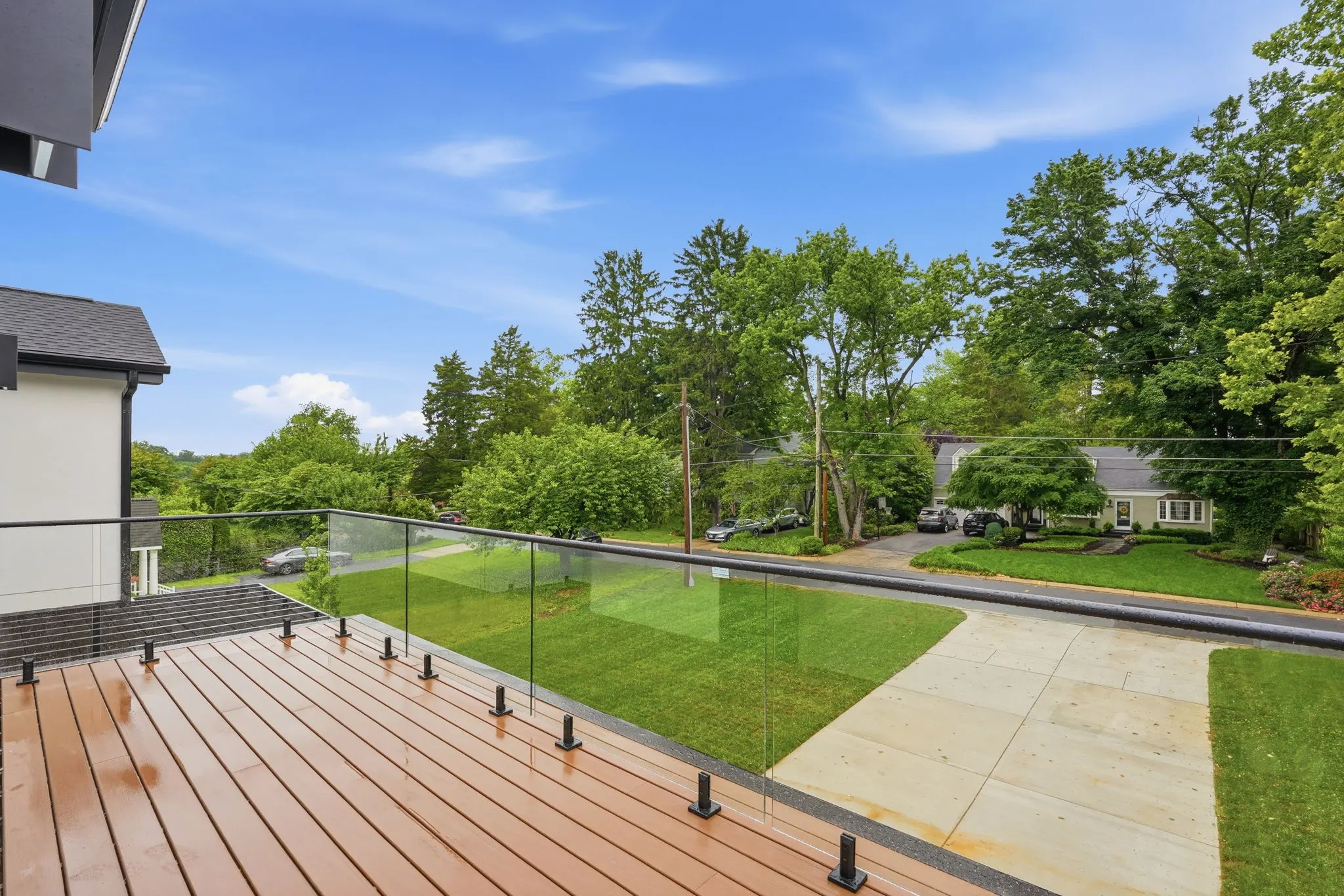 Raised deck with glass railing overlooking landscaped yard