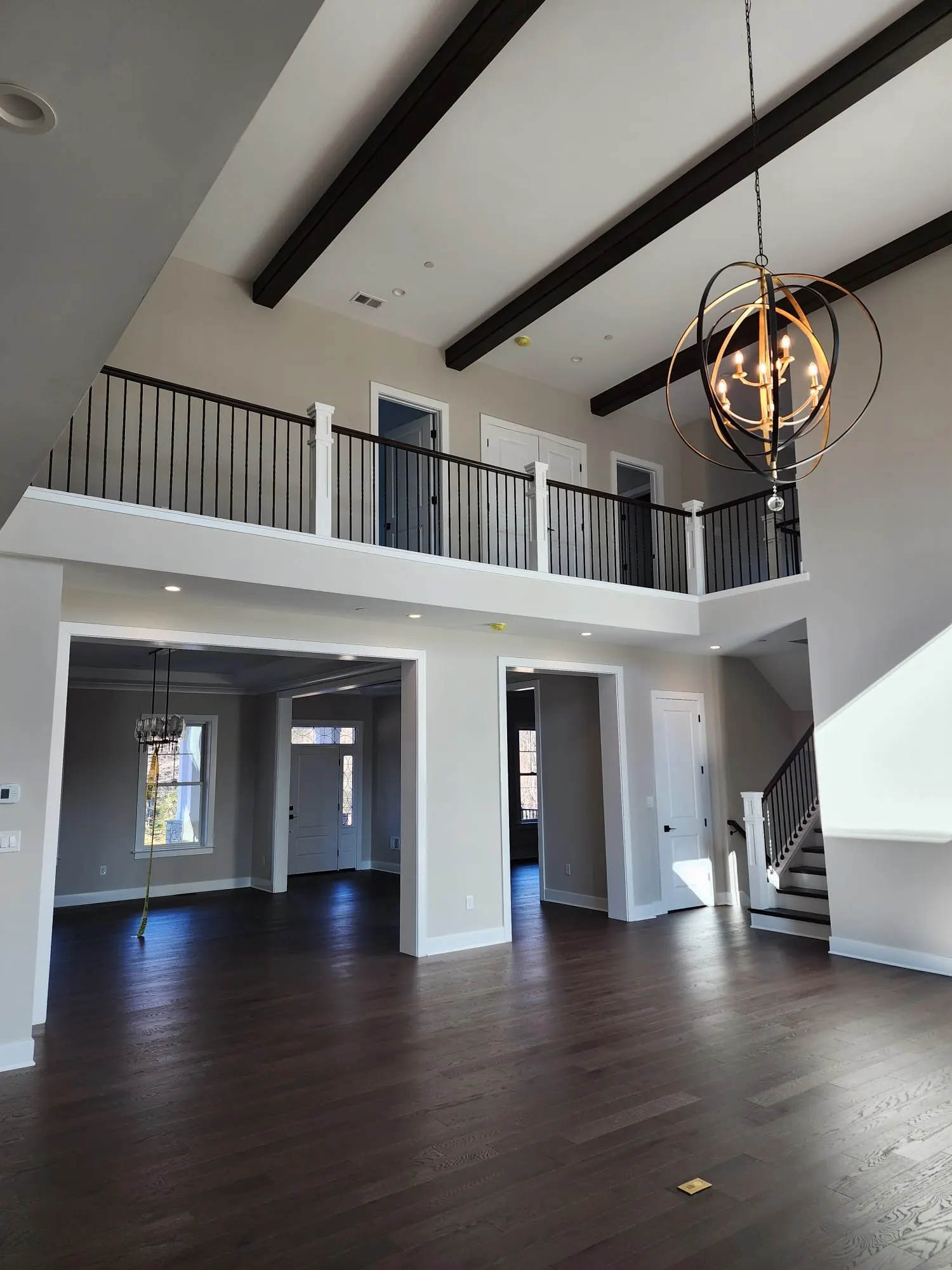 Two-story great room with balcony, chandelier, dark wood floors