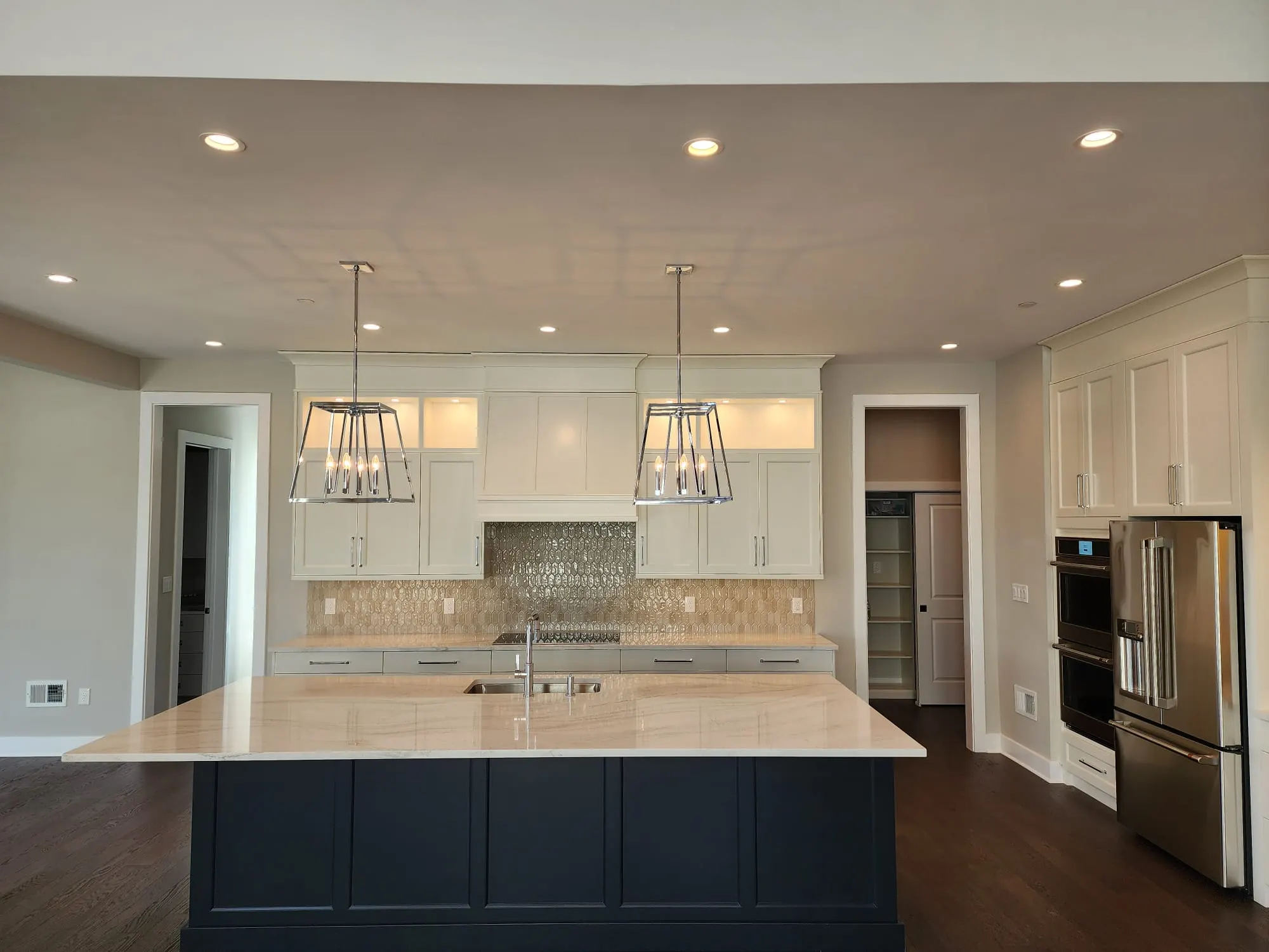 White kitchen with navy island and chrome pendant lights
