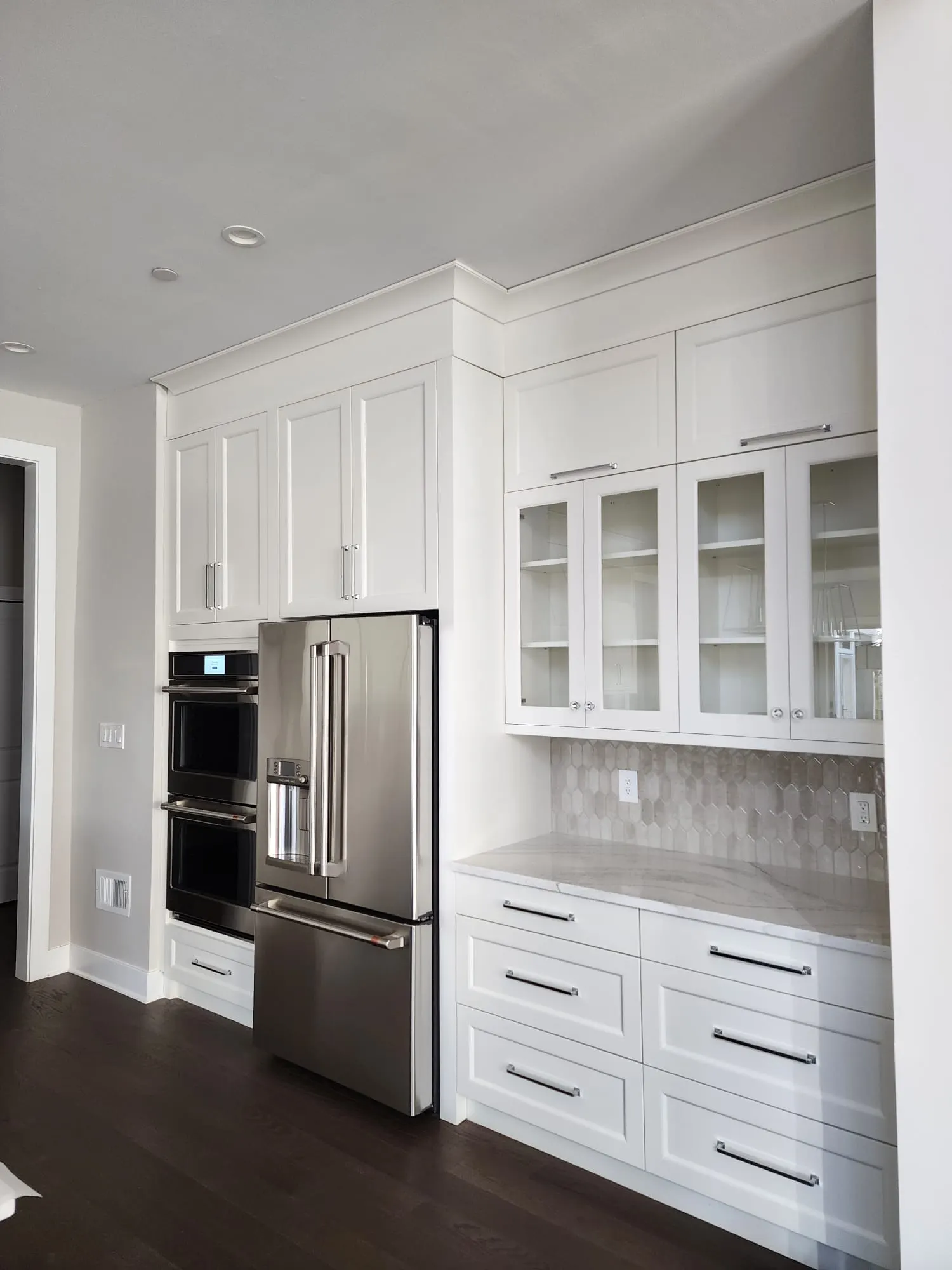 Double wall ovens, refrigerator, and glass-front cabinets