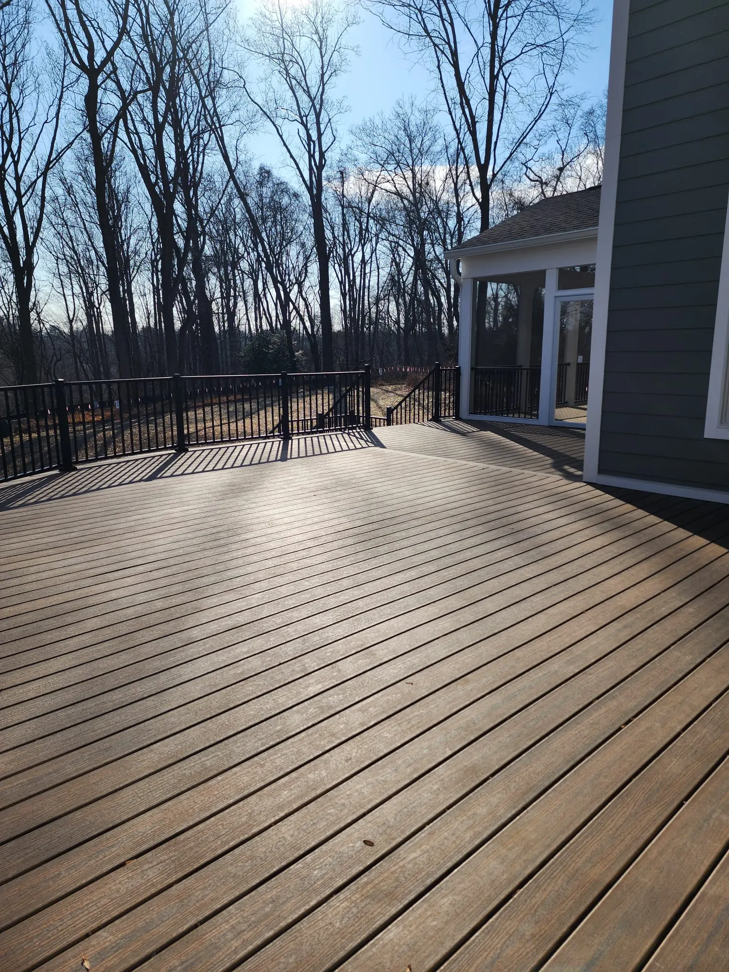 Large composite deck with black railing and wooded view