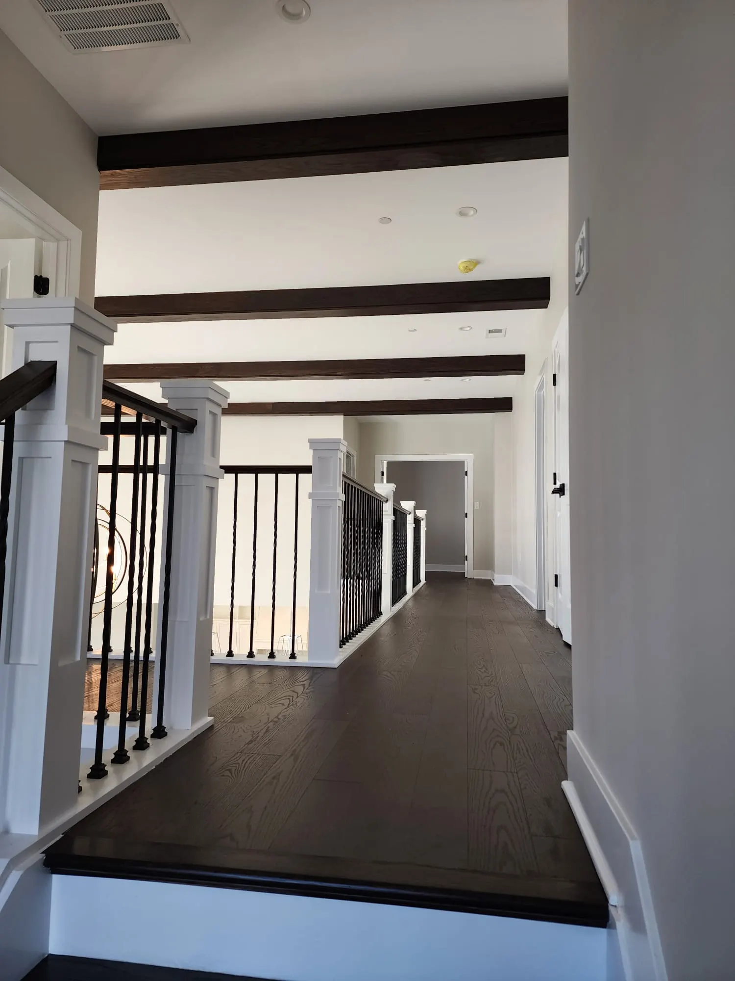 Upstairs hallway with dark wood beams and iron balusters