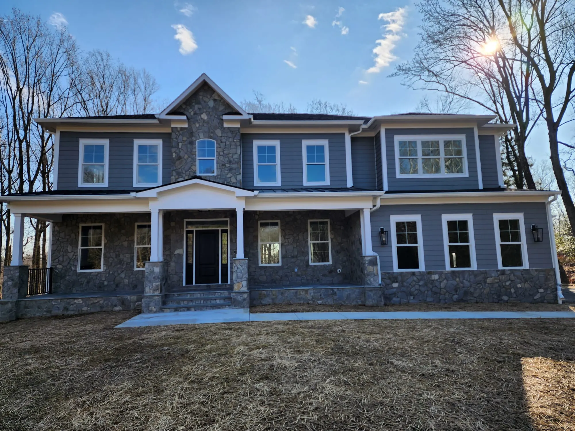 Front facade with stone base, blue-gray siding, covered porch