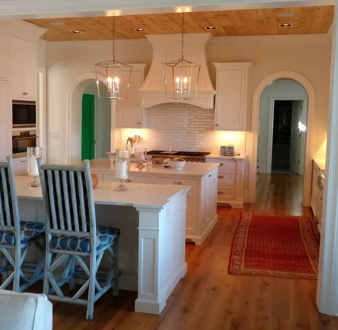 White kitchen with two islands, lantern pendants, and wood plank ceiling