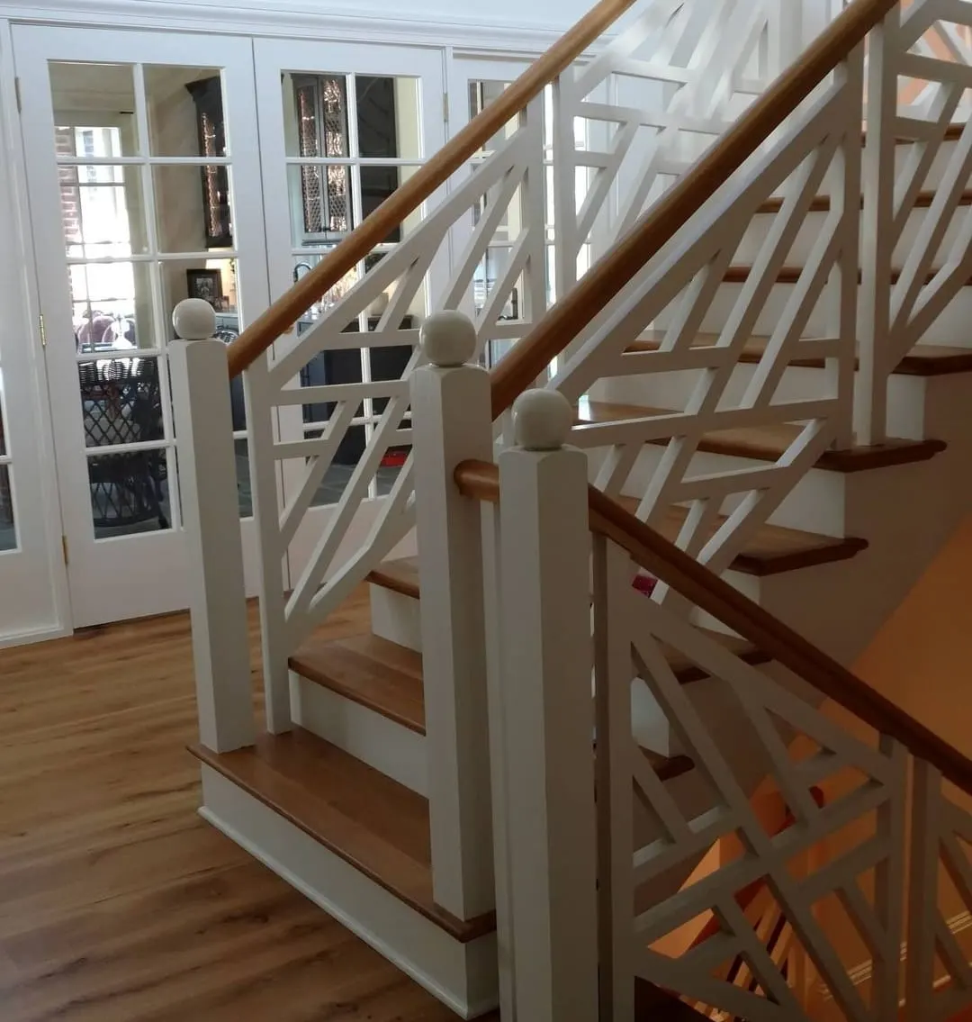 Staircase with white geometric fretwork railing and oak treads