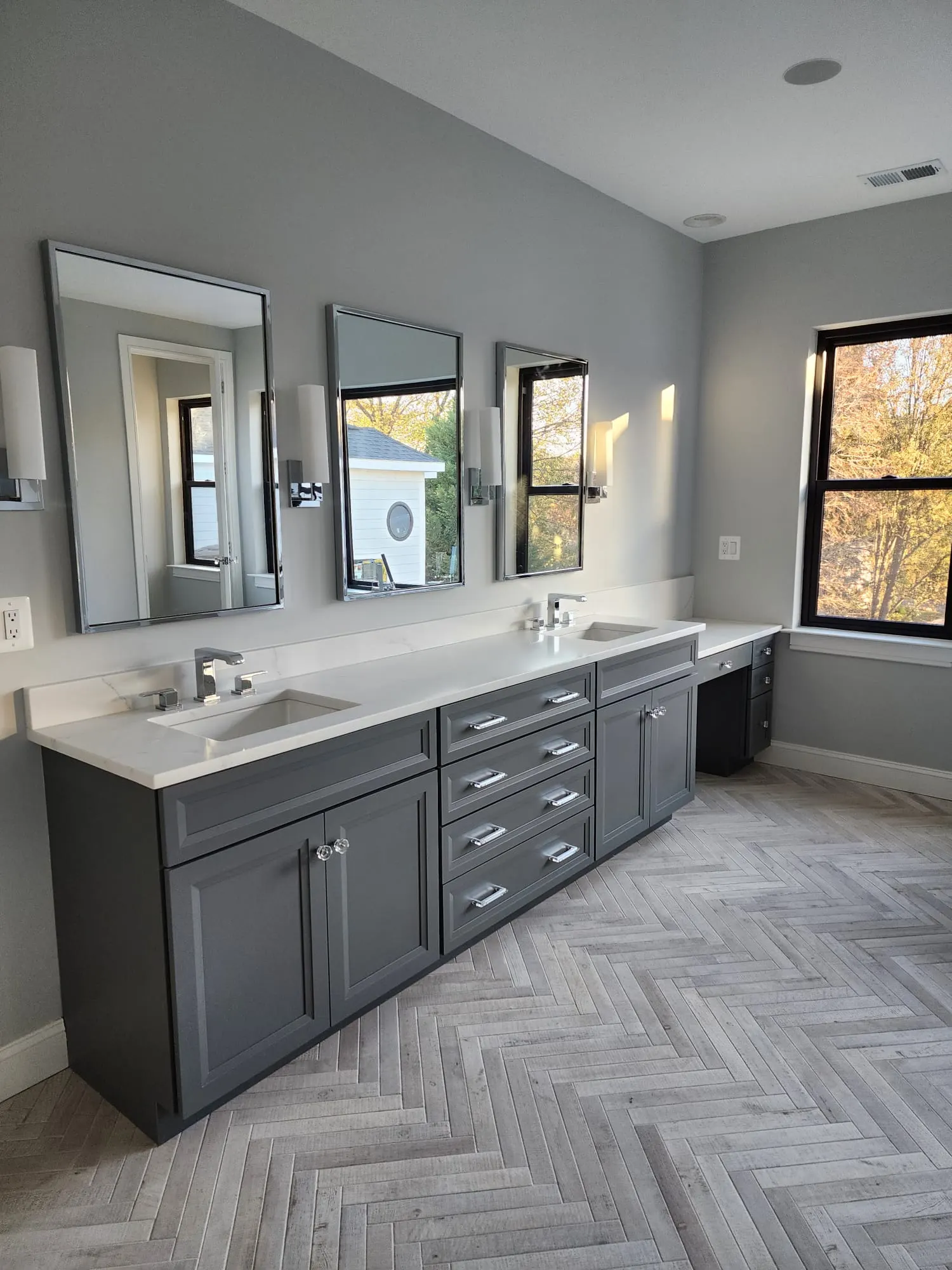 Primary bathroom with double gray vanity and herringbone tile floor
