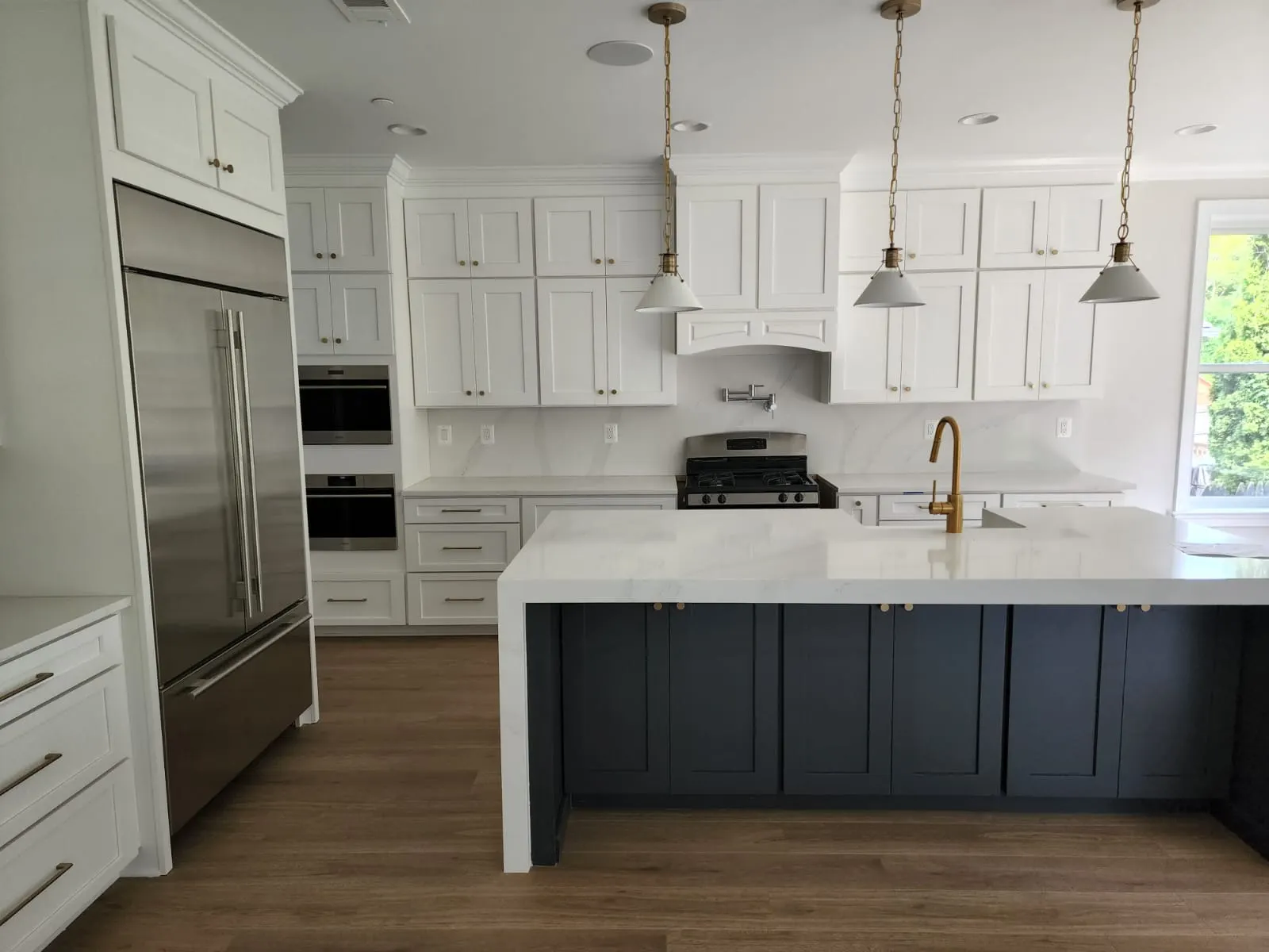 White kitchen with navy island, brass fixtures, and pendant lighting