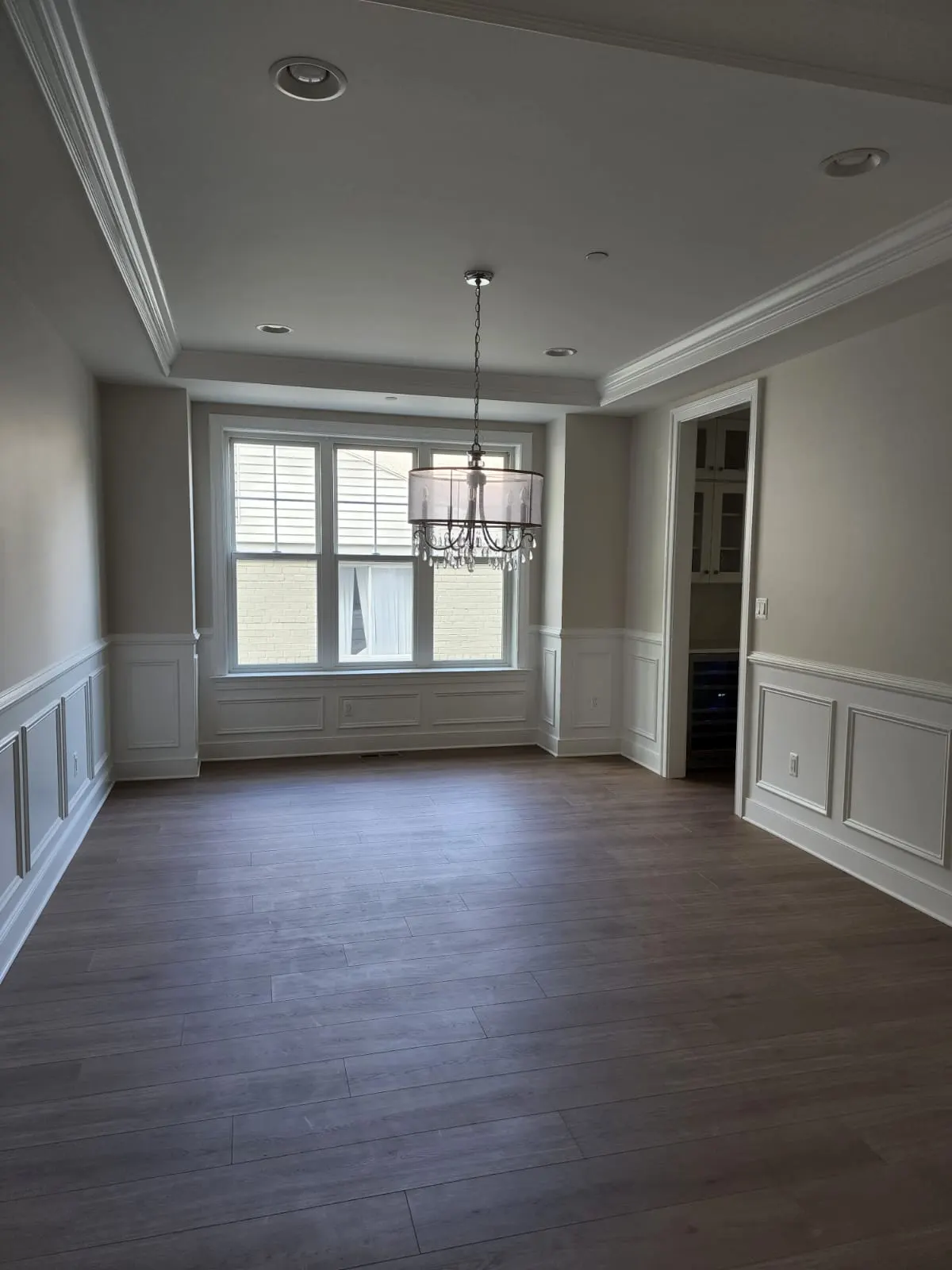 Dining room with wainscoting, tray ceiling, and drum chandelier