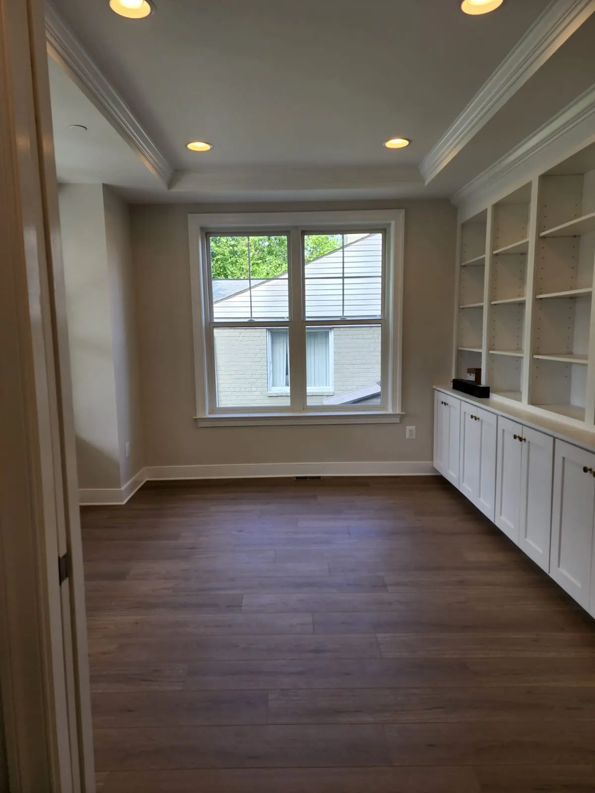 Office with built-in white shelving and a large window