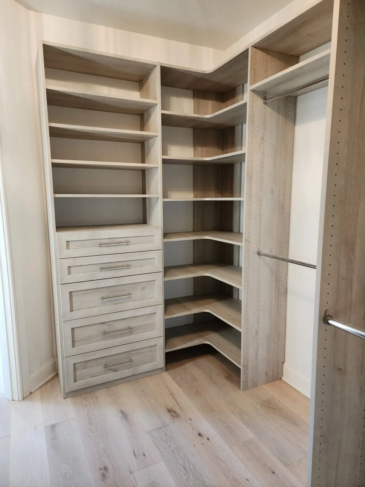 Walk-in closet with light wood built-in shelving and drawers
