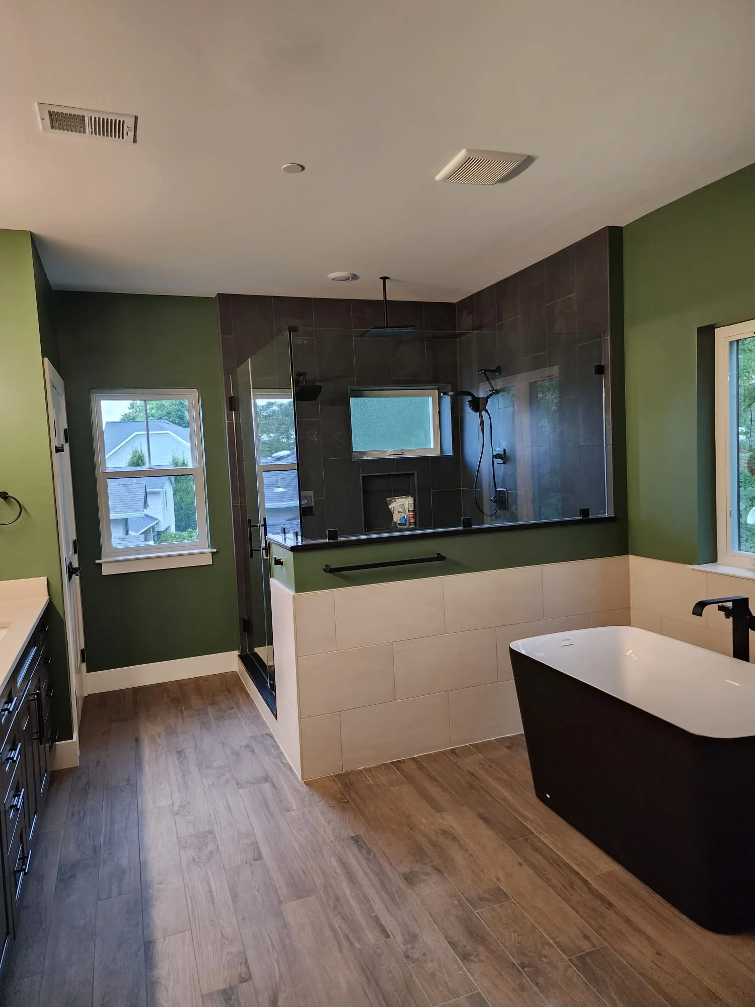 Primary bathroom with black freestanding tub, glass shower, green walls