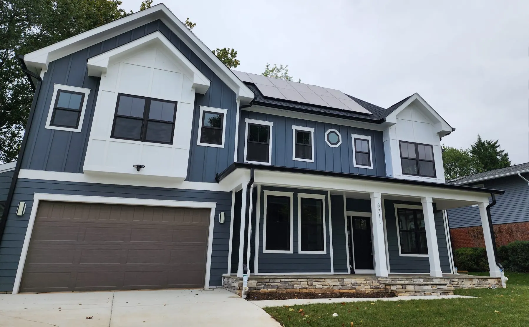 Angled front view of blue house with white trim and garage
