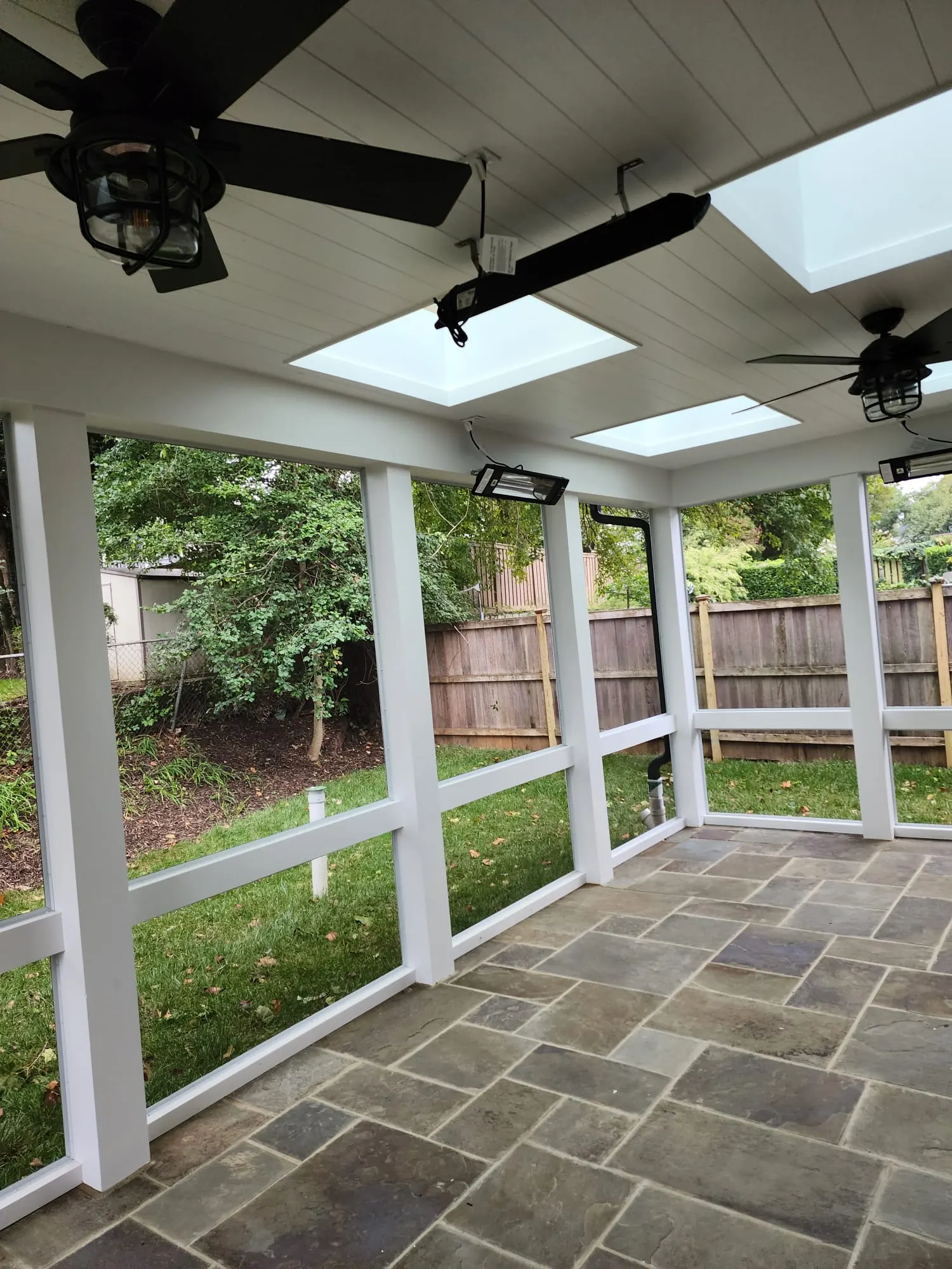 Screened porch with skylights, ceiling fans, and stone paver floor