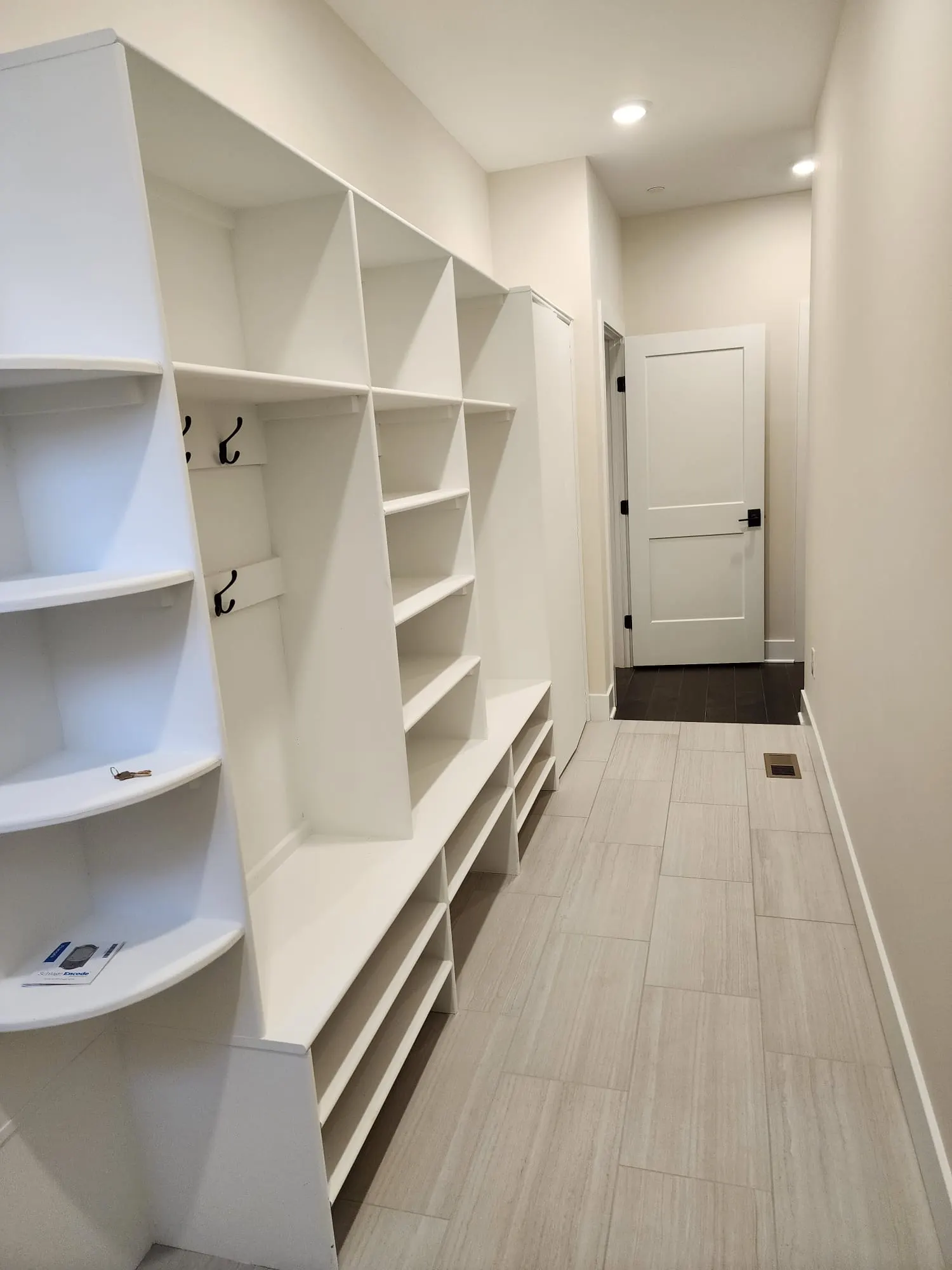 Mudroom with white built-in cubbies, coat hooks, and bench