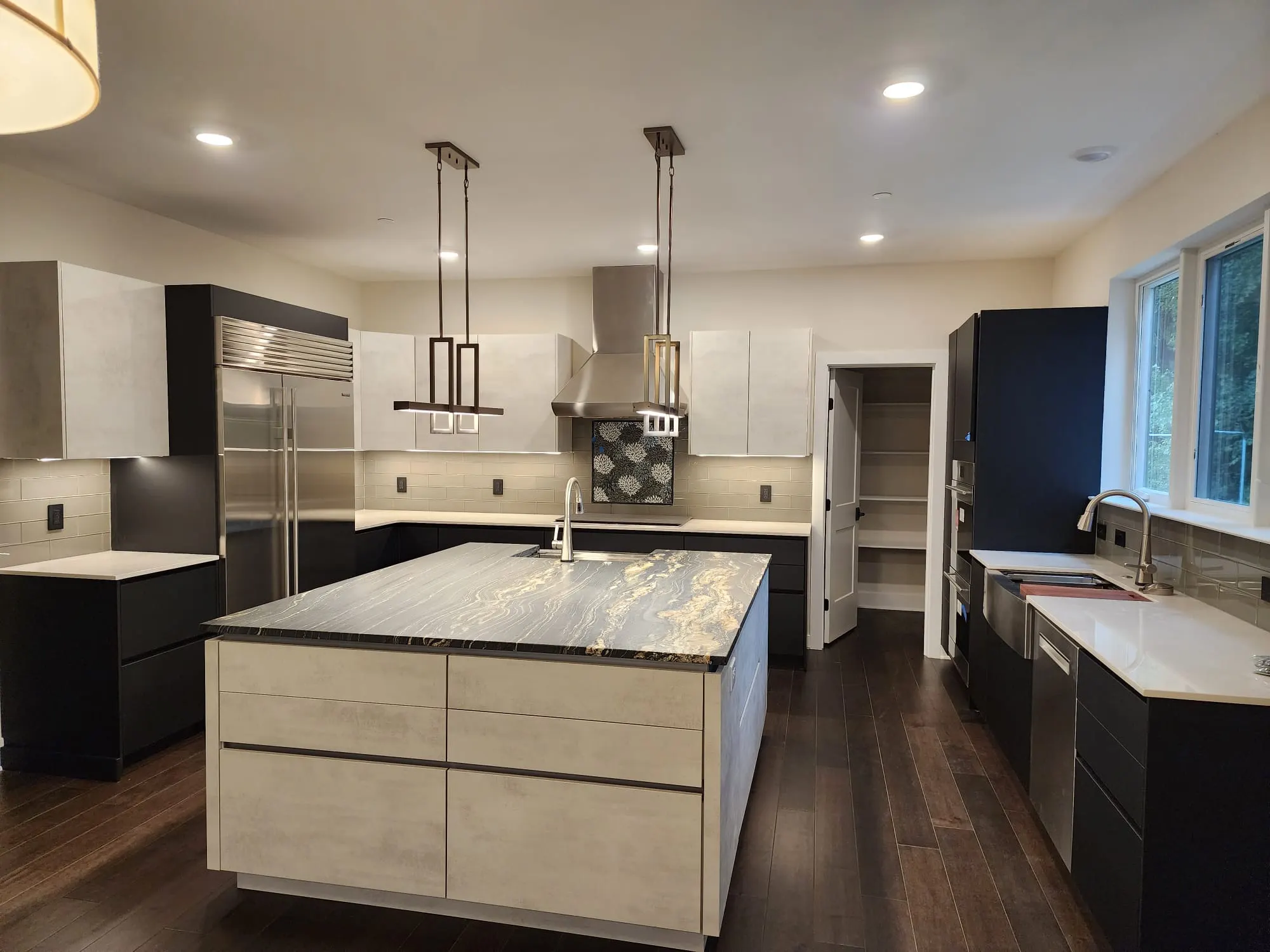 Kitchen with large stone-topped island, two-tone cabinets, pendant lights
