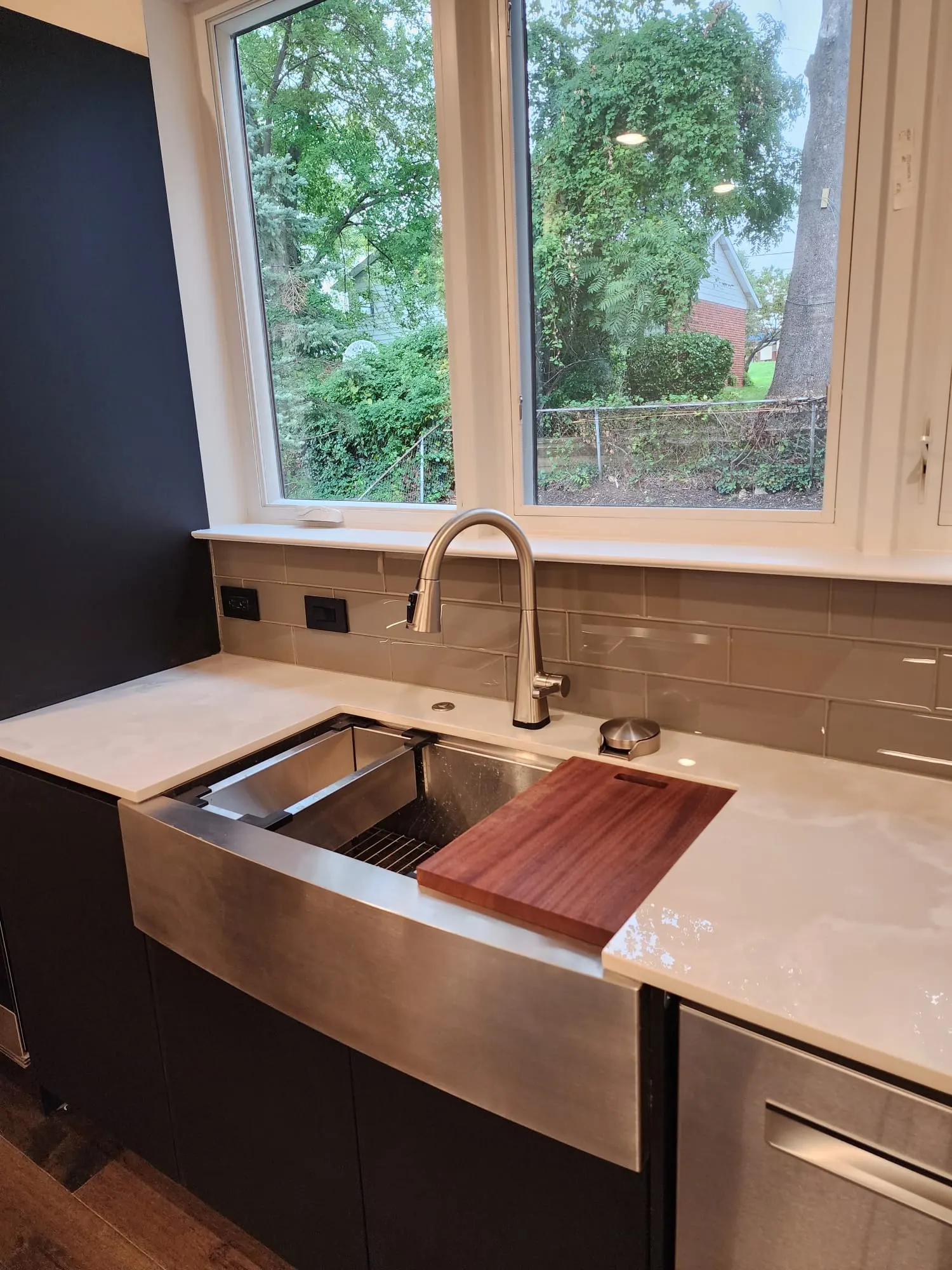 Stainless farmhouse sink with cutting board under kitchen windows