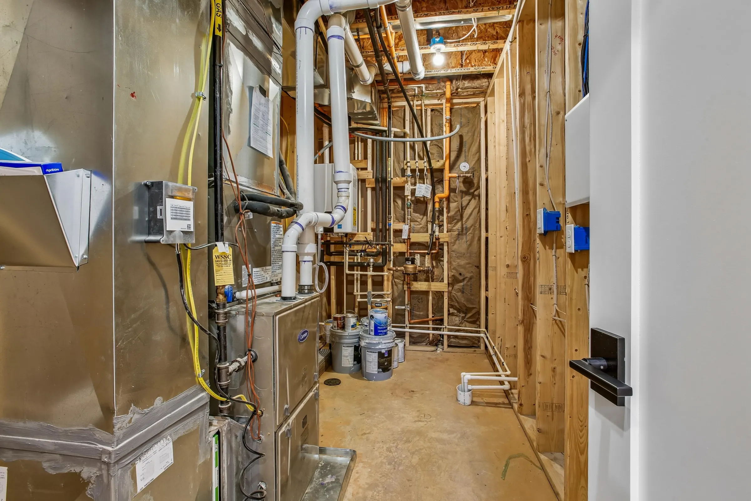 Mechanical room mid-build with new HVAC, plumbing lines, and open framing