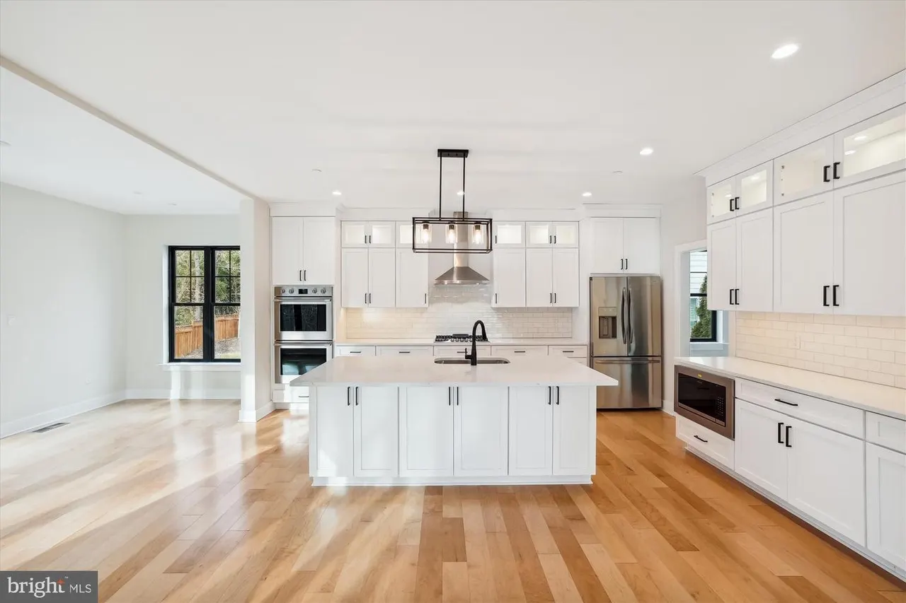 White kitchen with island, stainless steel appliances, wood floors