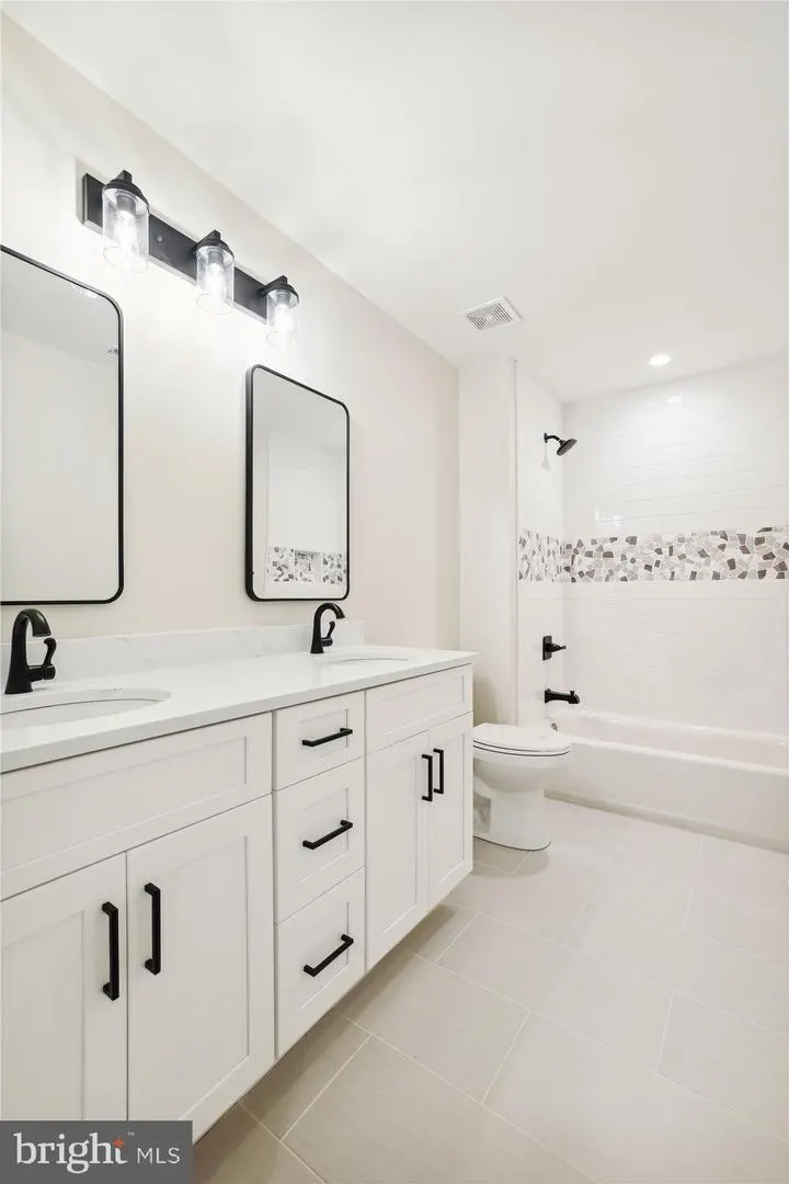 Secondary bathroom with white vanity and tiled shower
