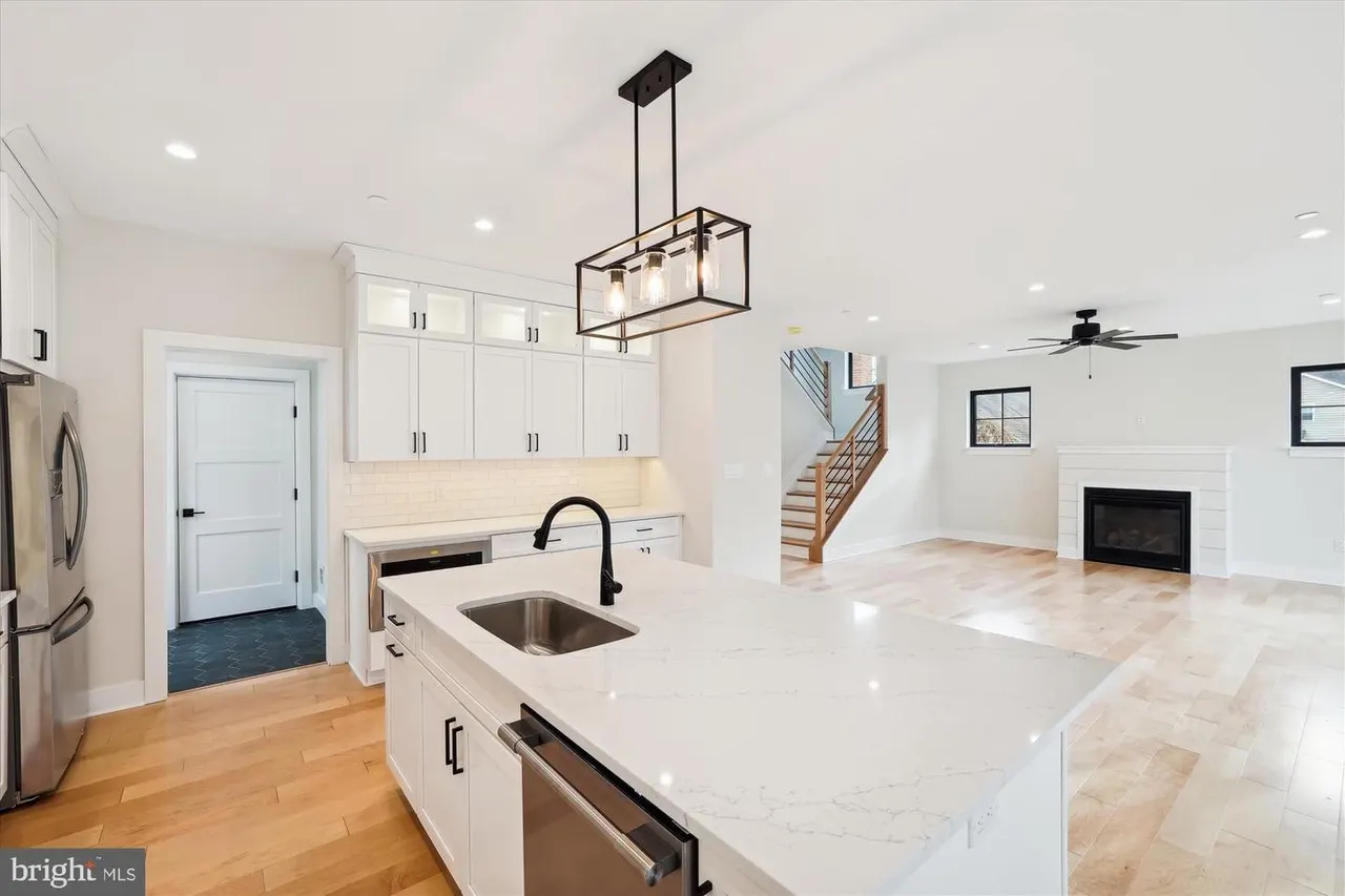 Kitchen with white cabinets, marble counters, and open living area