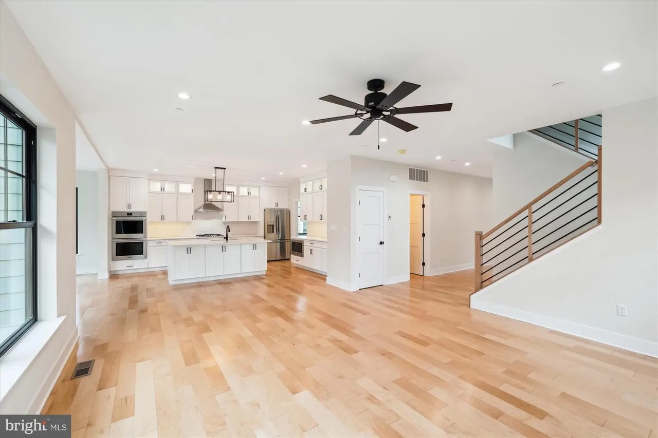 Open concept kitchen and great room with white cabinetry and wood floors