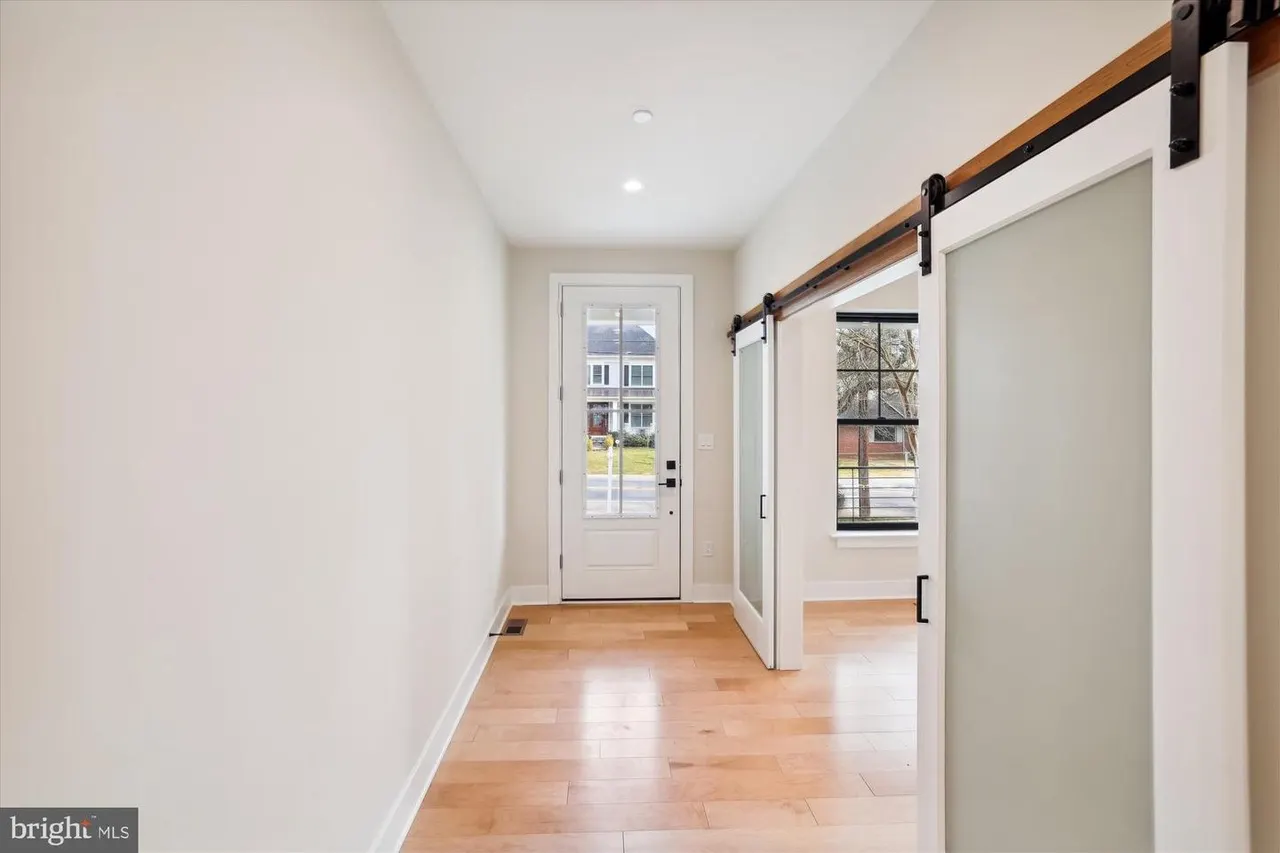 Foyer with white door, barn door, and hardwood flooring