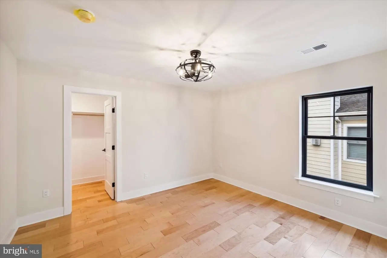 Bedroom with wood flooring, window, and closet entrance