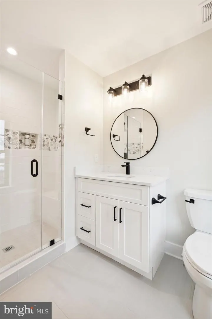 Master bathroom with white vanity, round mirror and glass shower enclosure