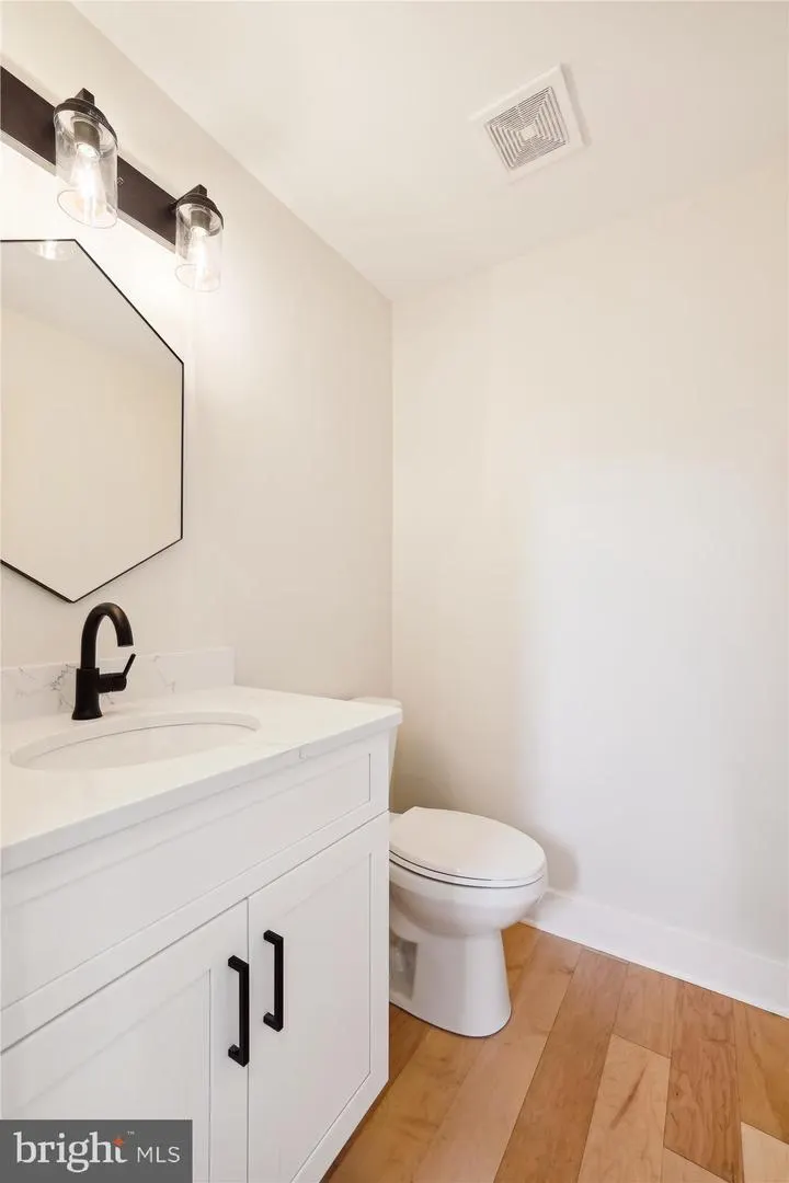 Powder room with white vanity, black faucet and hexagon mirror