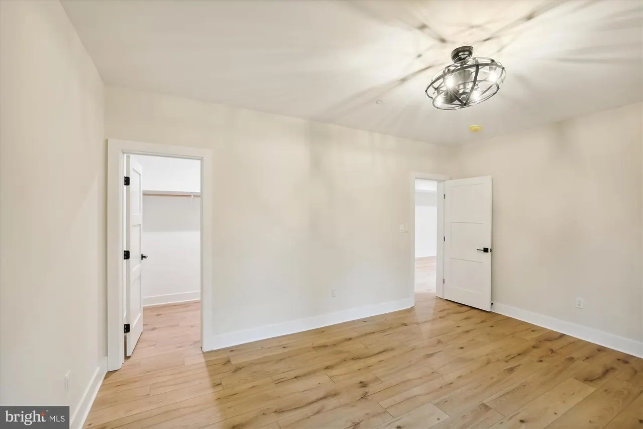 Bedroom with wood floors, white doors and ceiling fixture