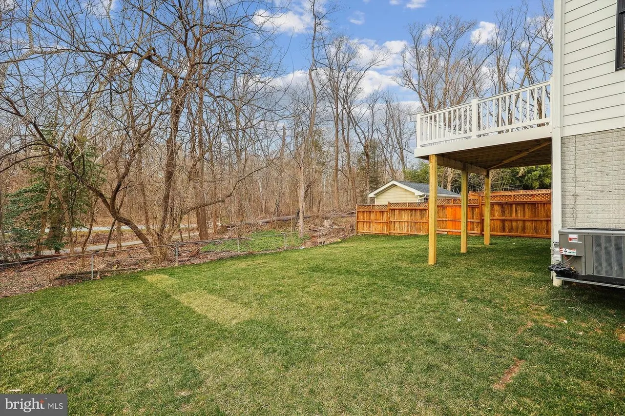 Backyard with wood deck, fence, and mature trees