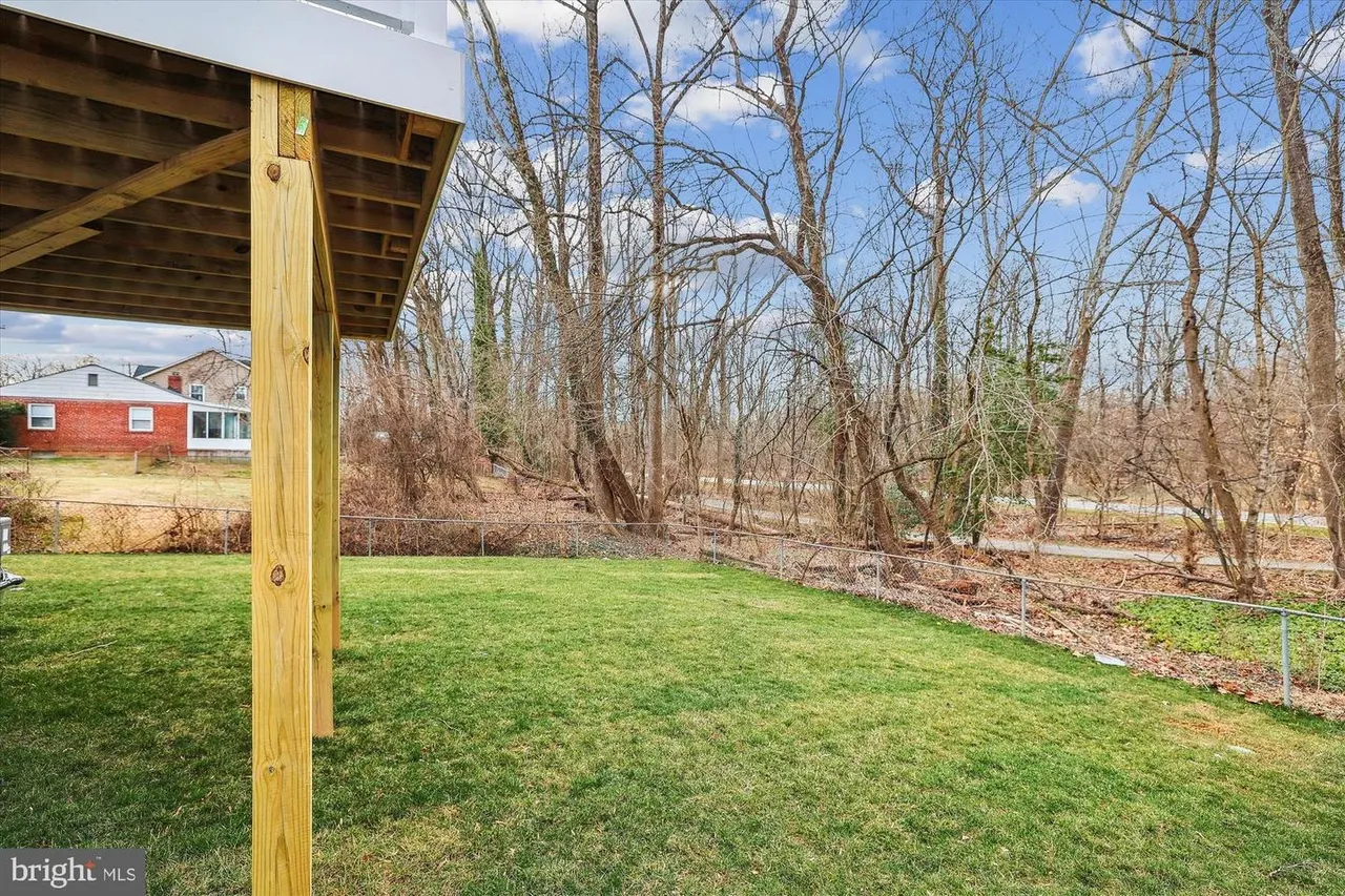 Pergola structure overlooking grassy yard and wooded area