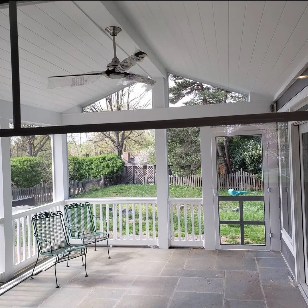 Screened porch with vaulted white ceiling, ceiling fan, and stone floor